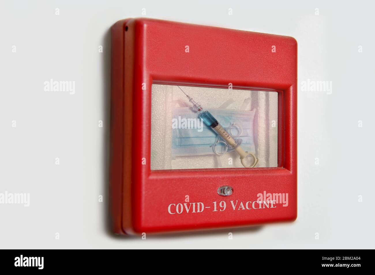 Image concept d'une seringue et d'un masque facial contenus dans une alarme murale d'urgence à utiliser avec les problèmes de Covid-19 et de coronavirus. Banque D'Images