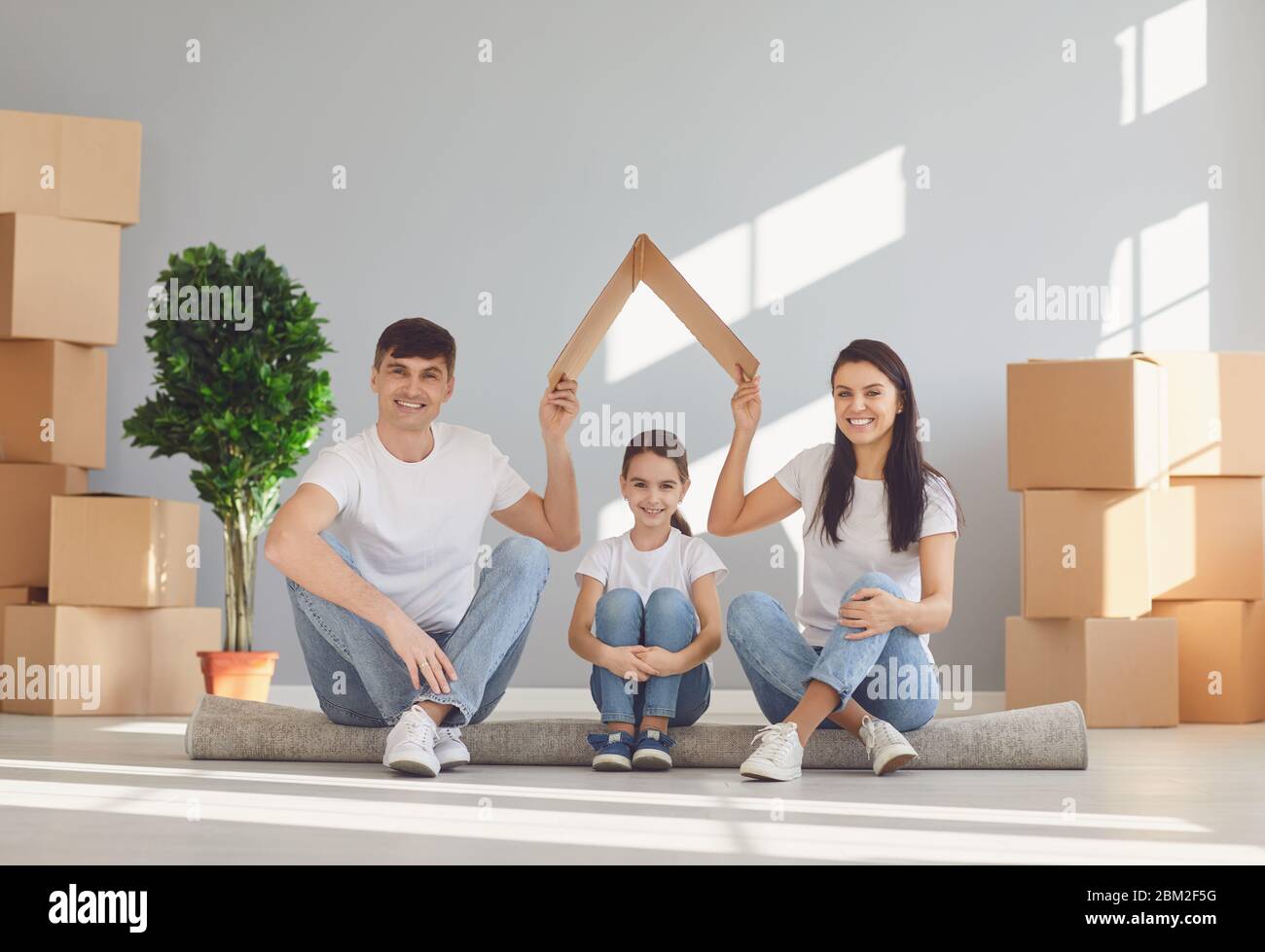 La famille souriante rit dans une nouvelle maison ensoleillée.mère père et fille de bébé dans une nouvelle maison. Le concept de déménagement de la nouvelle maison d'appartement déplacer h Banque D'Images