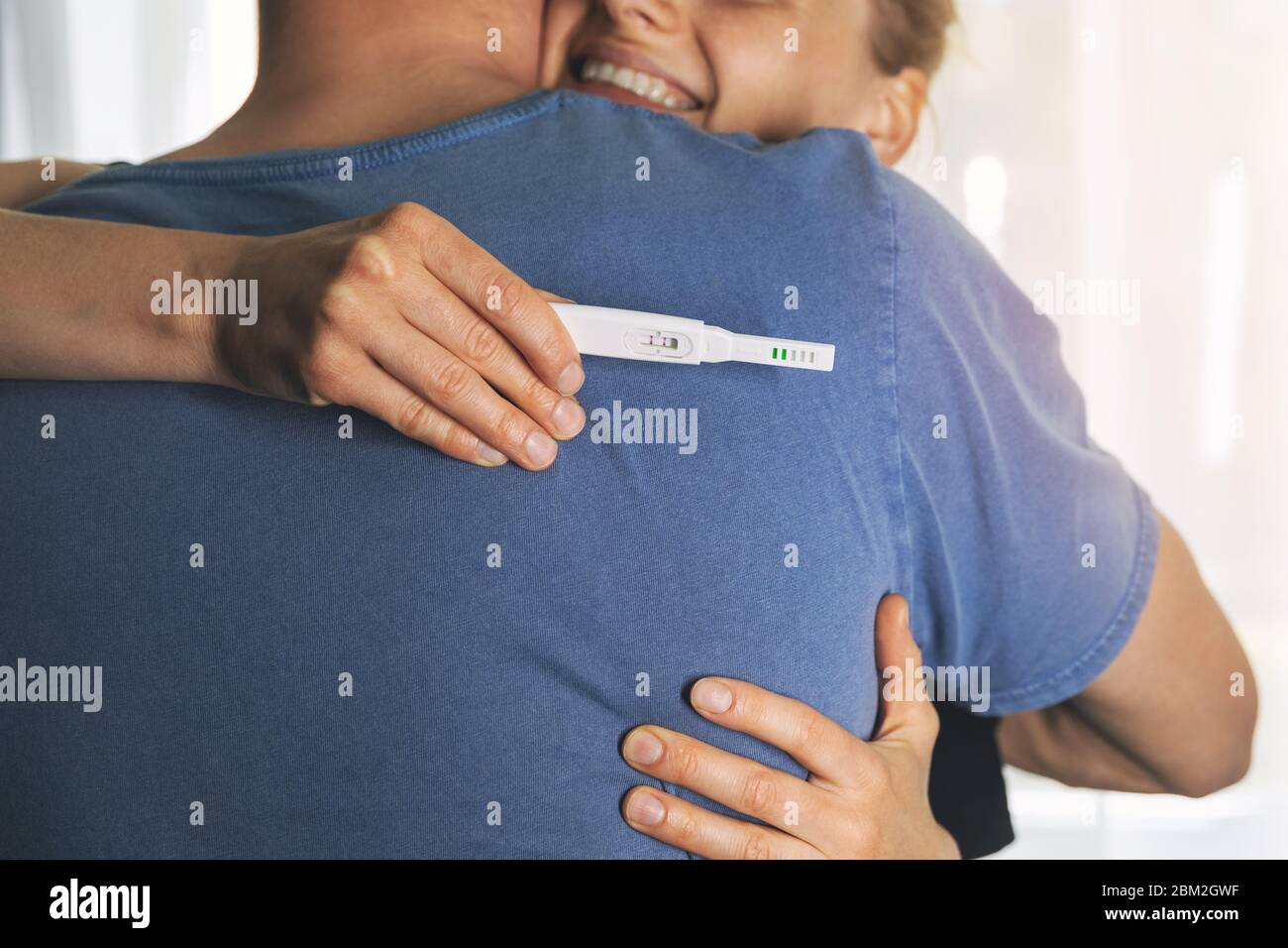 couple heureux se hembrassant après un test de grossesse positif Banque D'Images