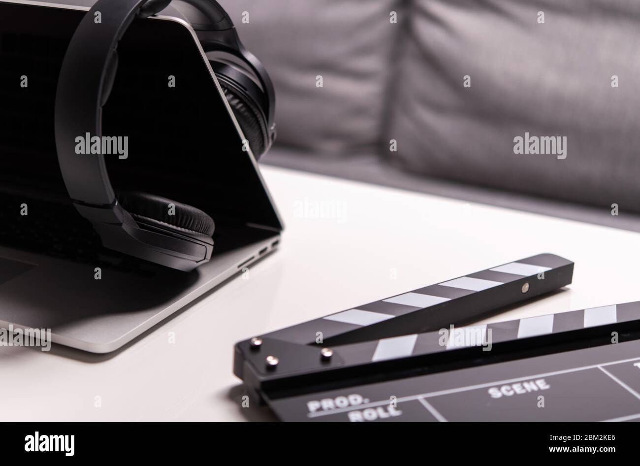 Gros plan sur Clapperboard ordinateur portable ouvert et casque noir sans fil sur table. Banque D'Images