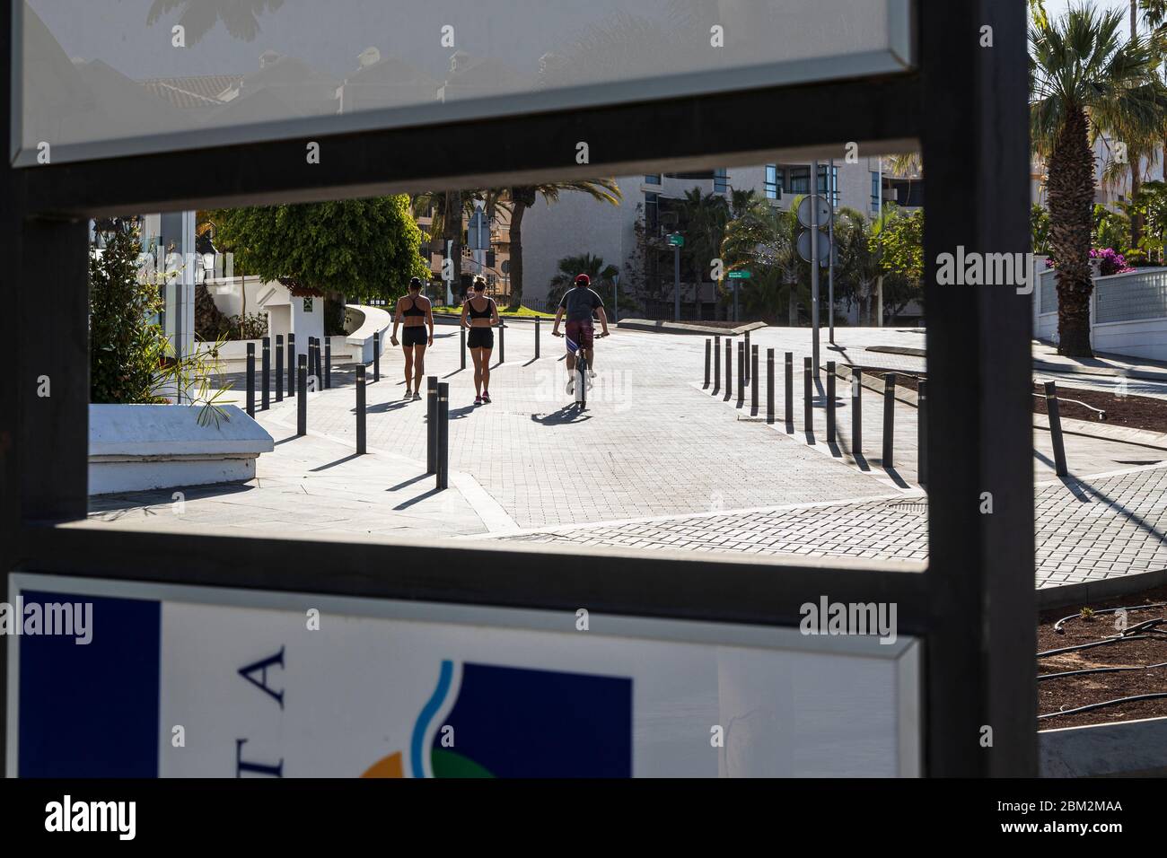 Un cycliste et deux jeunes femmes marchent sur la Calle Londres en maintenant la distance sociale pendant l'état d'urgence Covid 19 à Tenerife, île des Canaries Banque D'Images