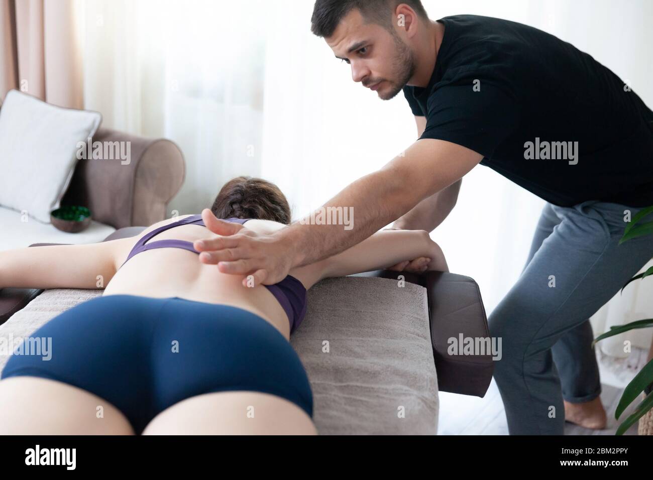 Jeune femme recevant un massage séesion à la maison par un physiothérapeute. Banque D'Images