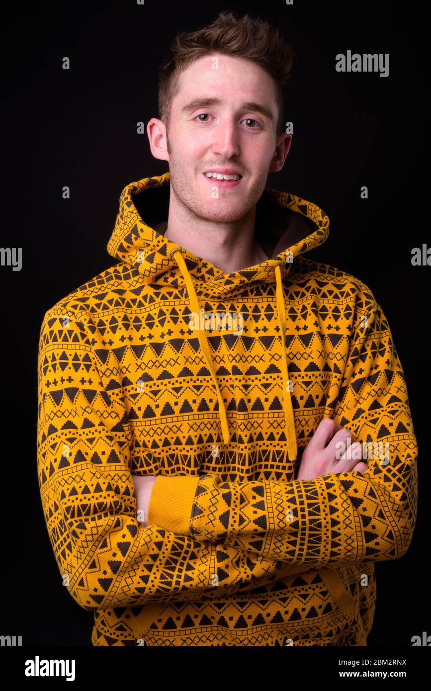 Happy young man wearing hoodie with arms crossed Banque D'Images