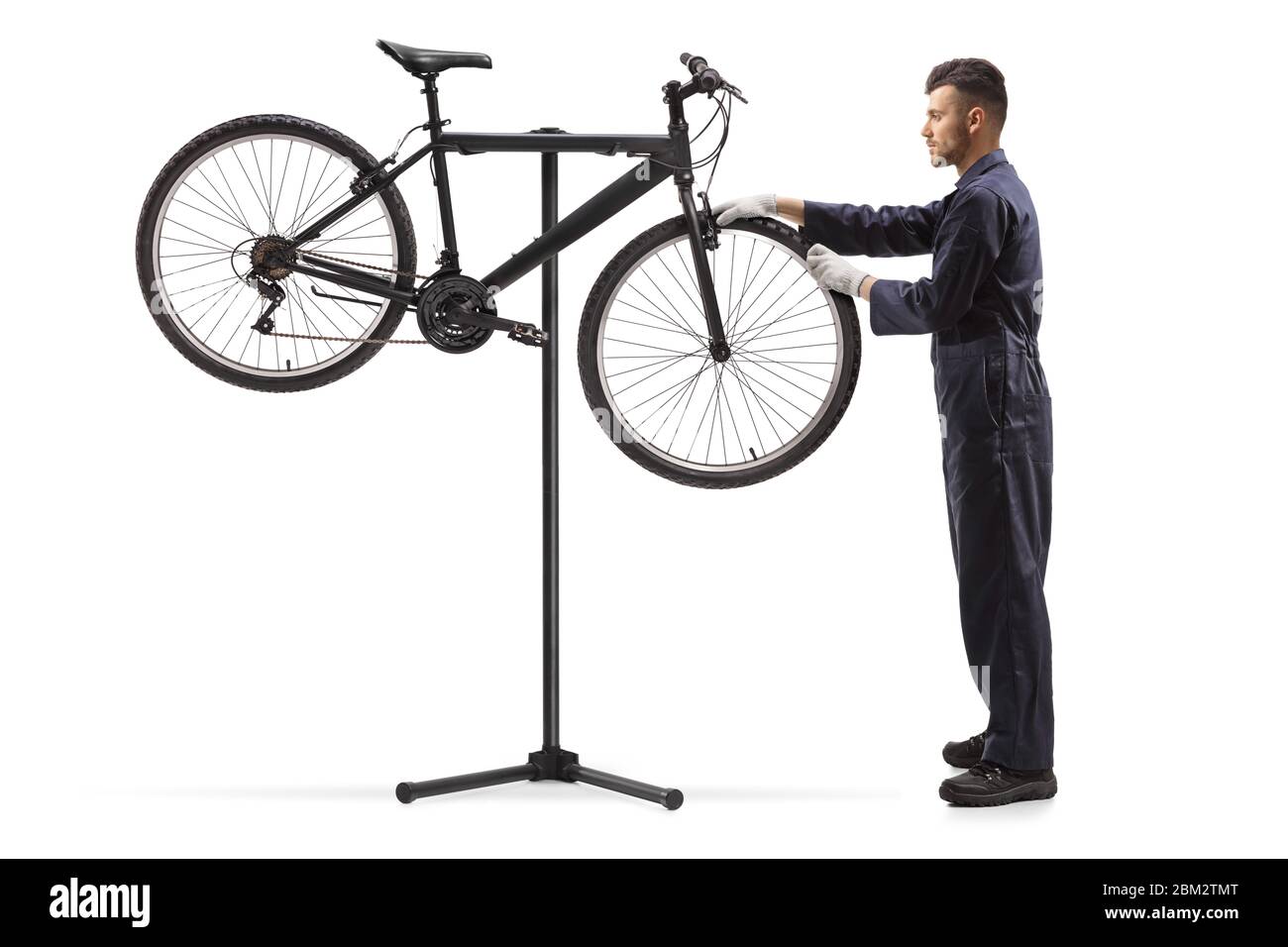 Plan en longueur d'un mécanicien de vélo réparant une roue de vélo isolée sur fond blanc Banque D'Images