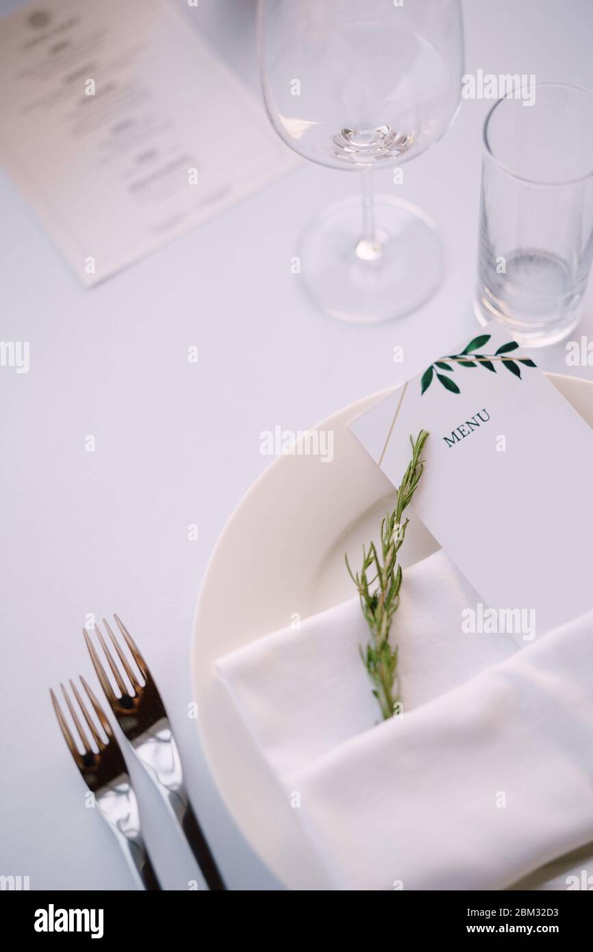 Réception de table de mariage. Assiette blanche avec serviette en tissu  avec menu en papier et branche de romarin, sur fond de nappe blanche Photo  Stock - Alamy