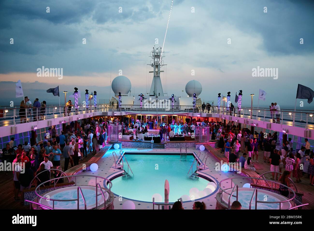 Une fête et une célébration colorées se déroulant au crépuscule sur le pont principal d'un bateau de croisière de luxe Banque D'Images