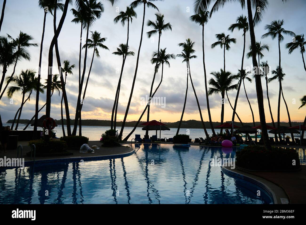 Un coucher de soleil magnifique vue depuis un complexe sur une île isolée de Fidji avec la silhouette de palmiers Banque D'Images