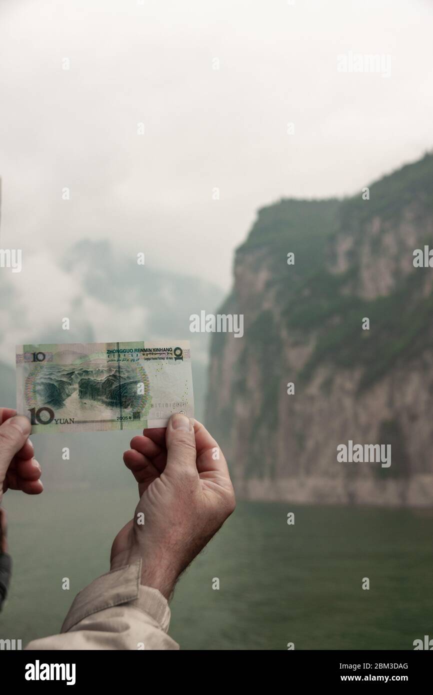 Baidicheng, Chine - 7 mai 2010 : gorge de Qutang sur le fleuve Yangtze. Gros plan de mains tenant un projet de loi de 10 yuans avec la même falaise rocheuse pour la montagne et la manne verte Banque D'Images