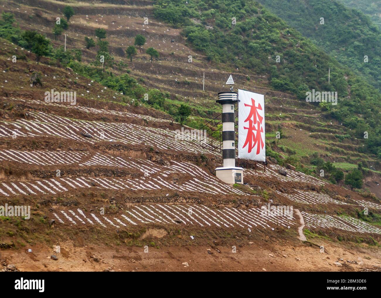 Baidicheng, Chine - 7 mai 2010 : gorge de Qutang sur le fleuve Yangtze. Parcelles agricoles brunes sur une pente de montagne verte avec un panneau de navigation rouge et une si légère Banque D'Images