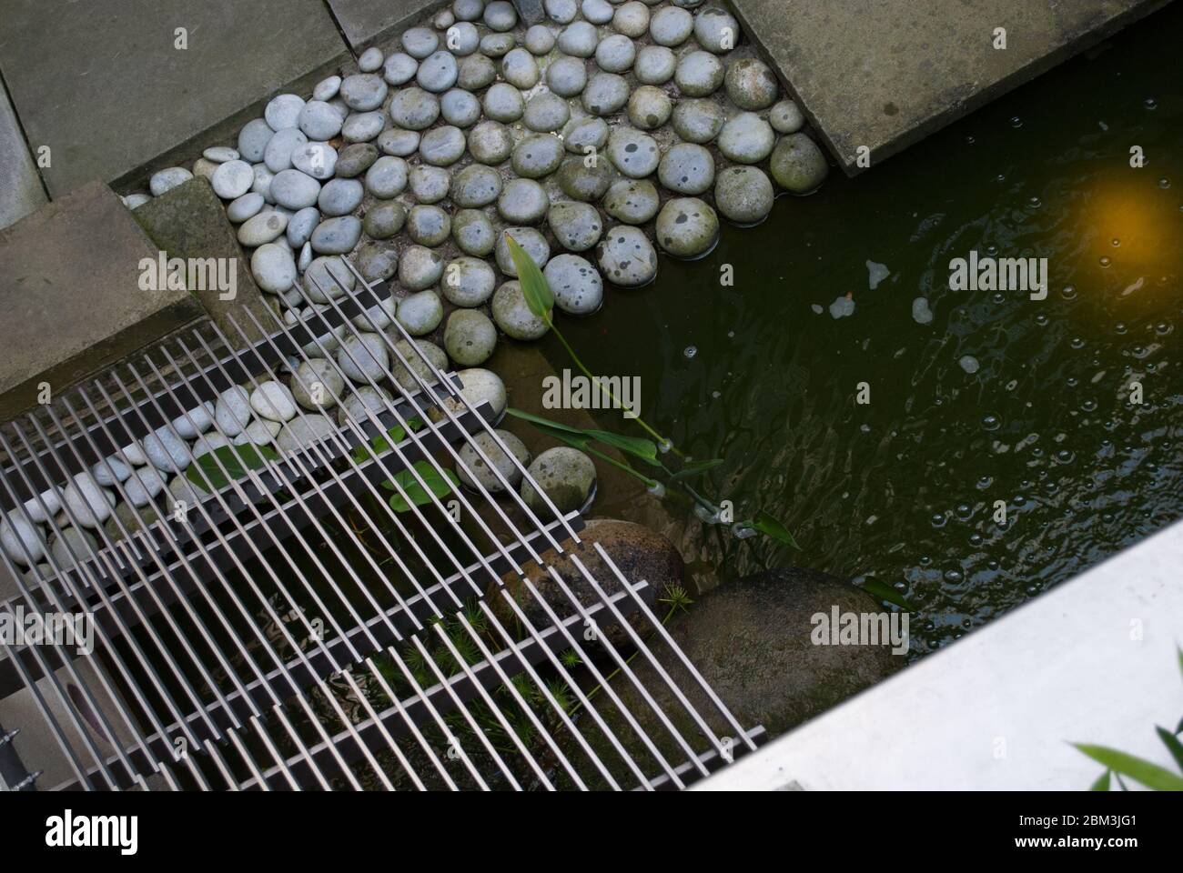 Inspiration architectural détail Edging Pebbles Grill grille Stone Water nature dans Garden Pond à Londres, Angleterre Banque D'Images