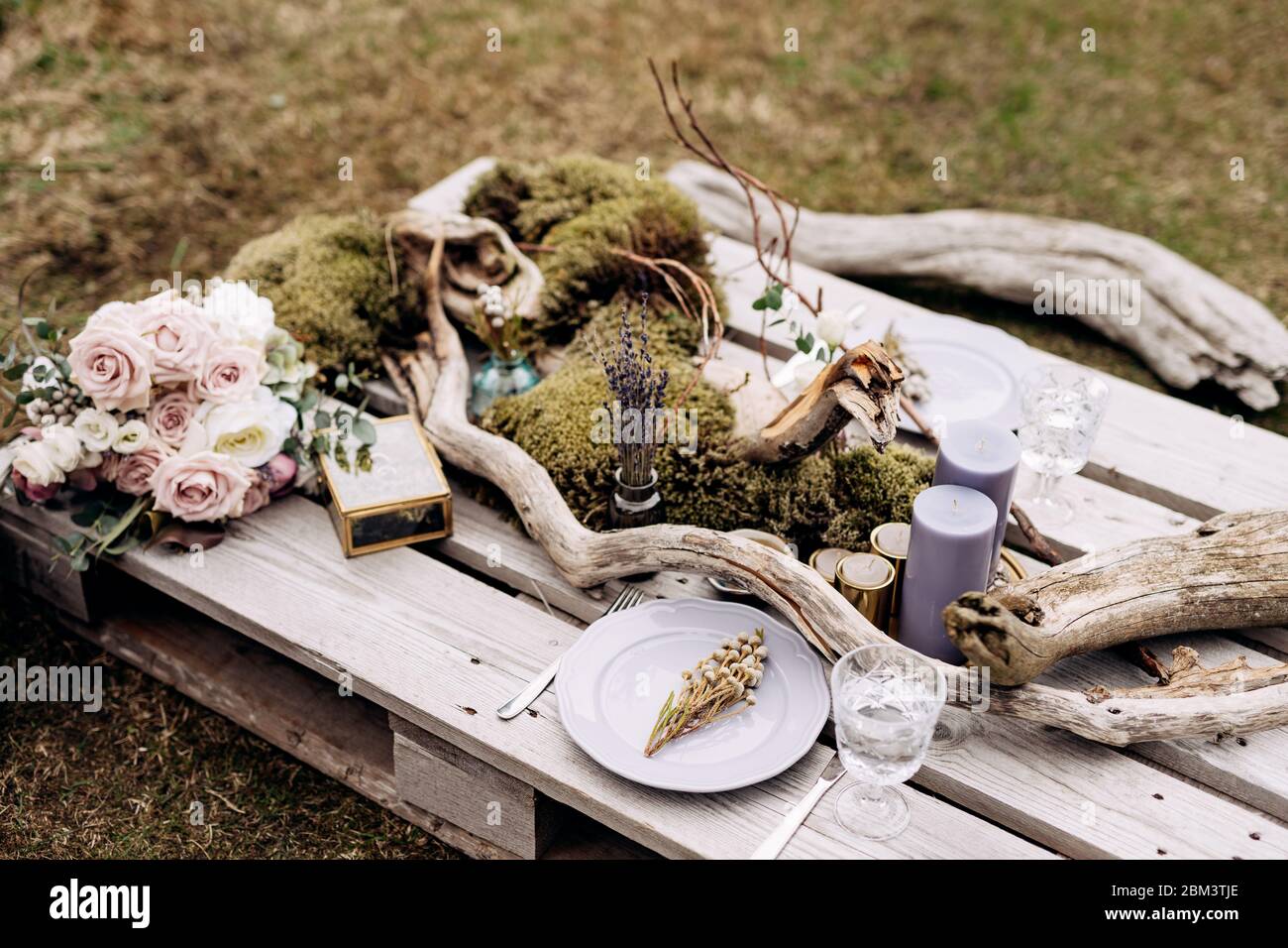 Réception de table de mariage. Une table impromptue pour deux de la palette de construction sur l'herbe grise en Islande. Plaque violet clair, accrocs, mousse Banque D'Images
