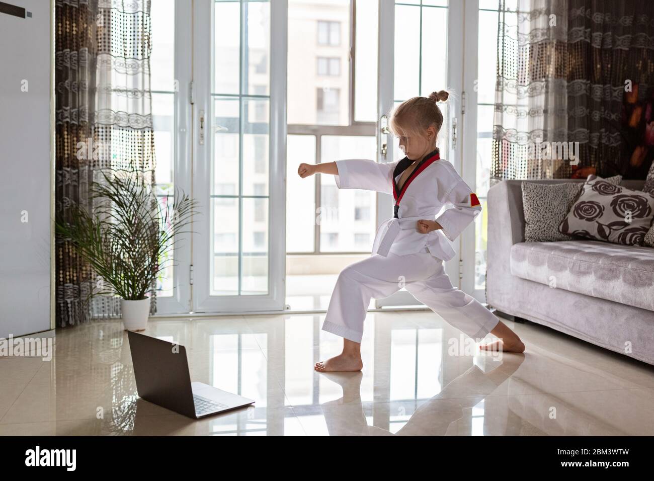 Taekwondo fille dans kimono avec ceinture blanche s'exerçant à la maison  dans le salon. Formation en ligne pendant le verrouillage du coronavirus  covid-19, l'auto-isolement et Photo Stock - Alamy