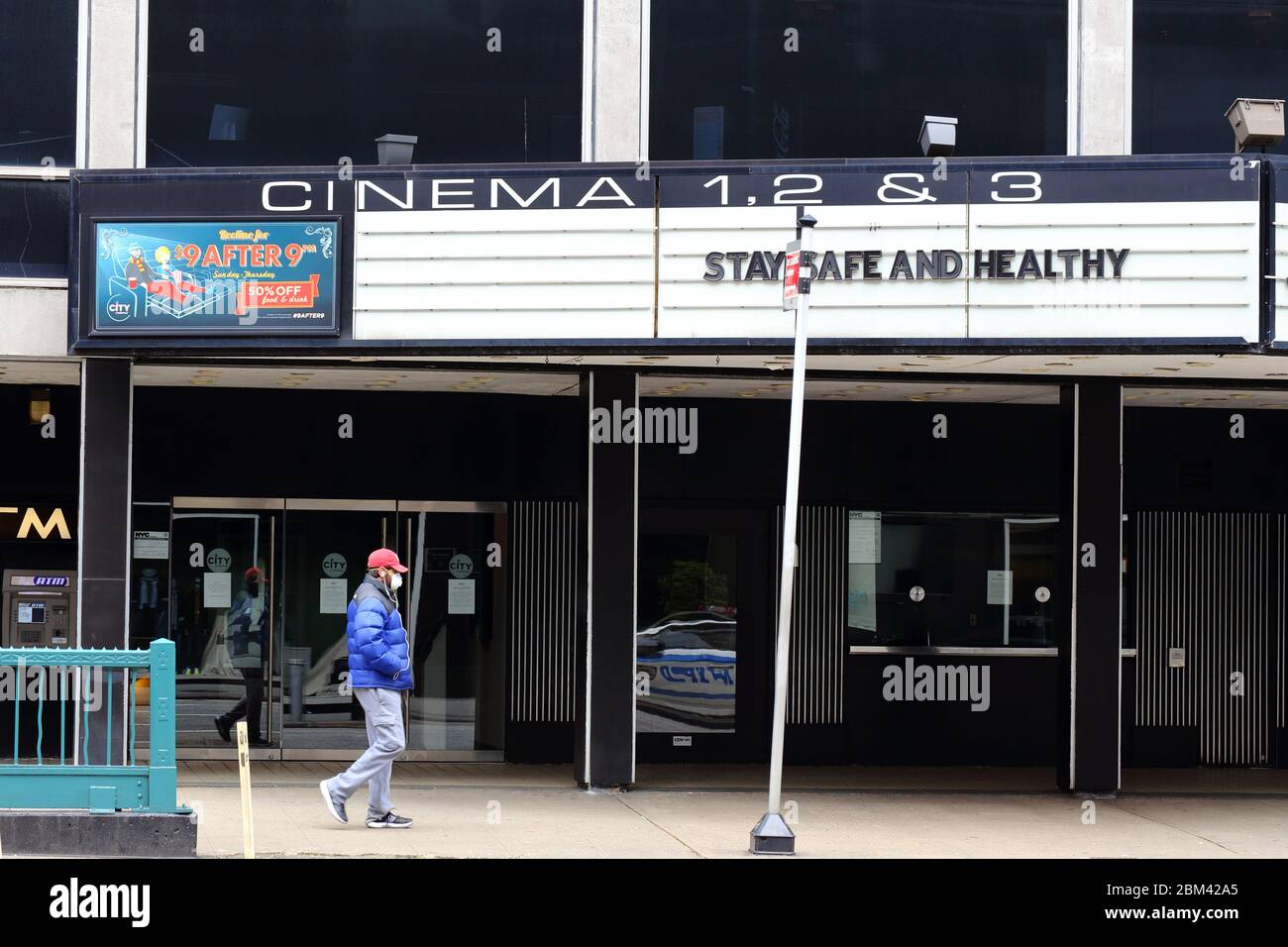 Une personne avec un masque passe devant un chapiteau de cinéma avec le message « Stay Safe and Healthy » à New York pendant le coronavirus. 29 avril 2020 Banque D'Images