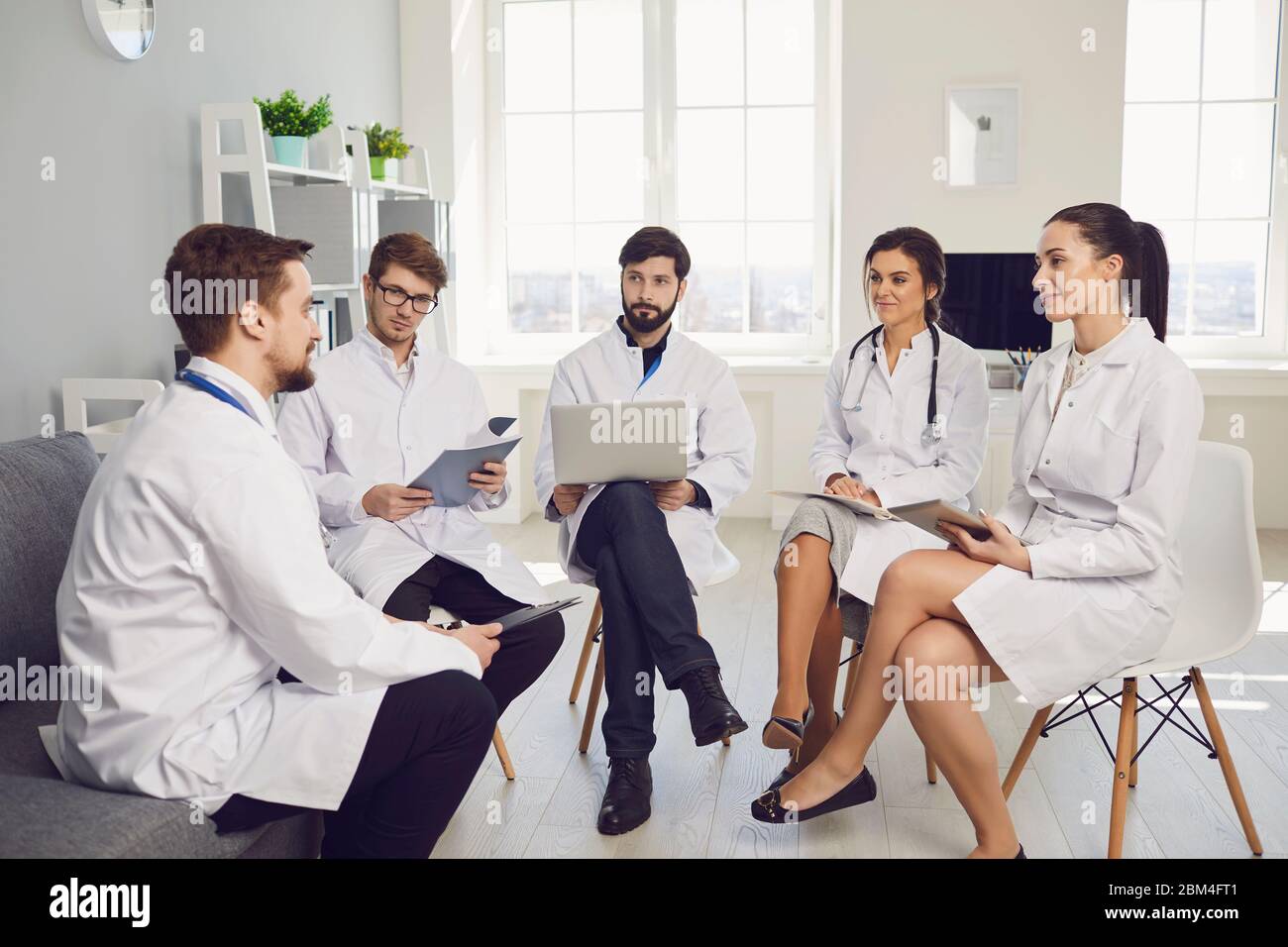 Un groupe de médecins praticiens en réunion discute du diagnostic d'un patient assis à un bureau dans un cabinet clinique. Médecins confiants à la conférence ta Banque D'Images