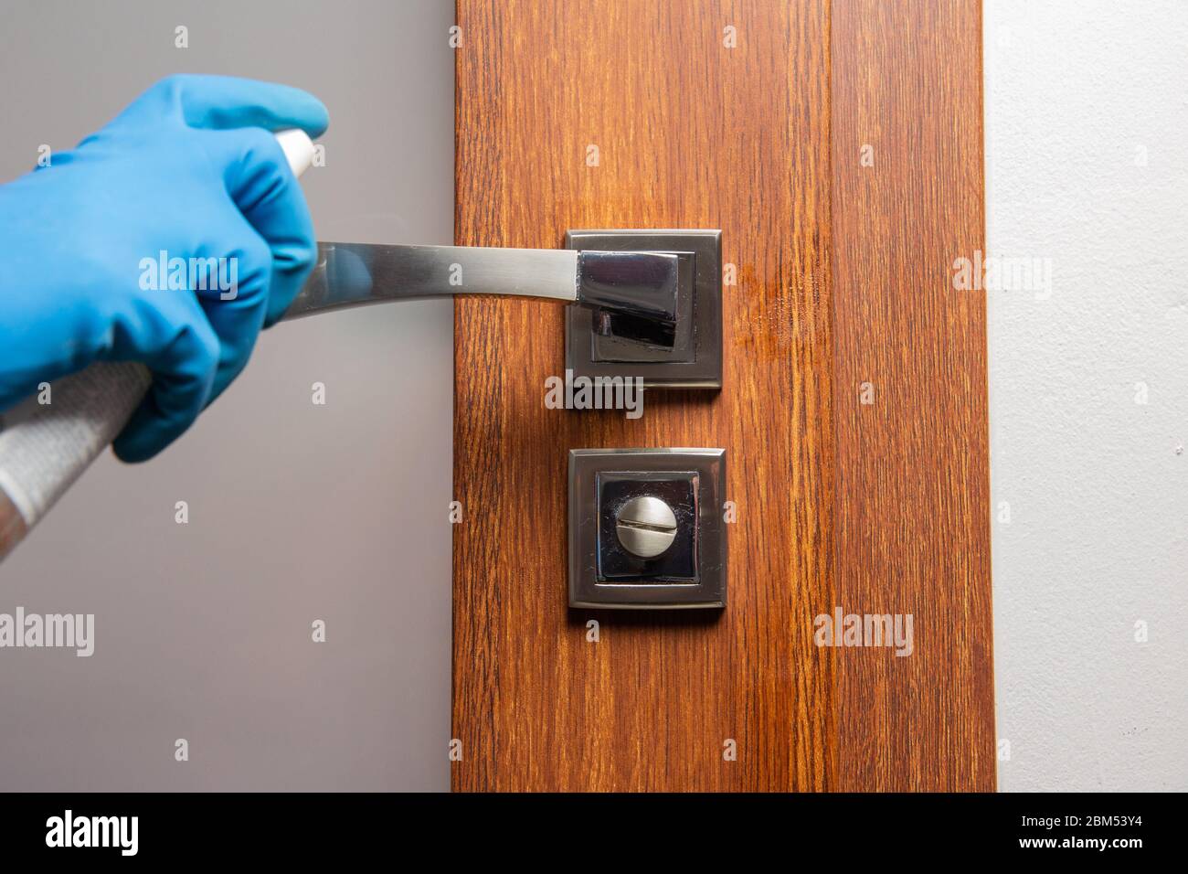 Désinfectez et nettoyez la poignée de porte avec un spray et un chiffon, prévention de la propagation des virus Banque D'Images
