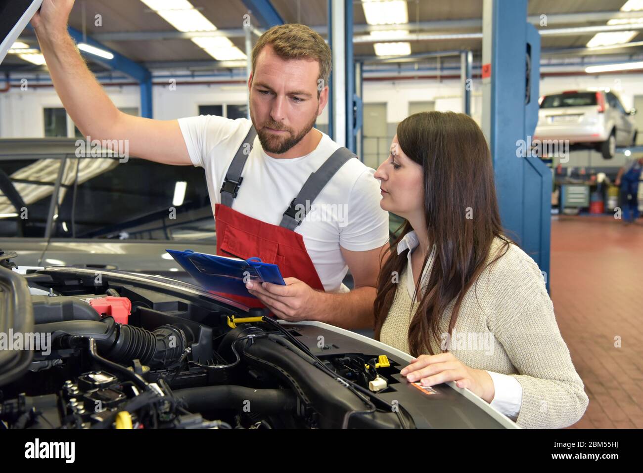 Service client : le mécanicien automobile et le client discutent de la réparation d'un véhicule sur site Banque D'Images