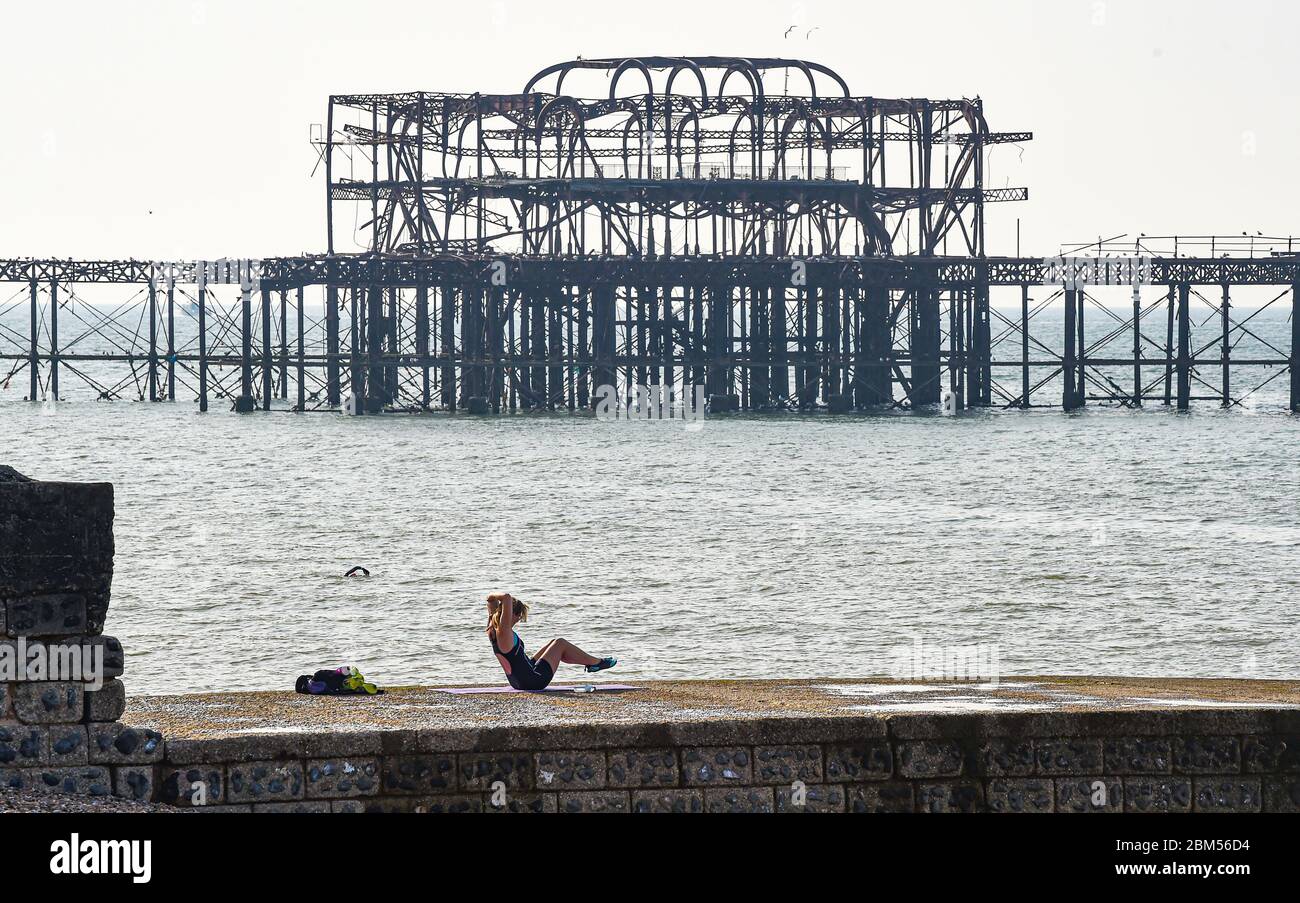 Brighton UK 7 mai 2020 - UNE jeune femme s'exerce au soleil près de la jetée ouest sur le front de mer de Brighton, sur une belle matinée ensoleillée pendant la crise pandémique du coronavirus COVID-19 . Le temps devrait être chaud et ensoleillé au cours des prochains jours avant de devenir plus frais le week-end . Crédit : Simon Dack / Alamy Live News Banque D'Images