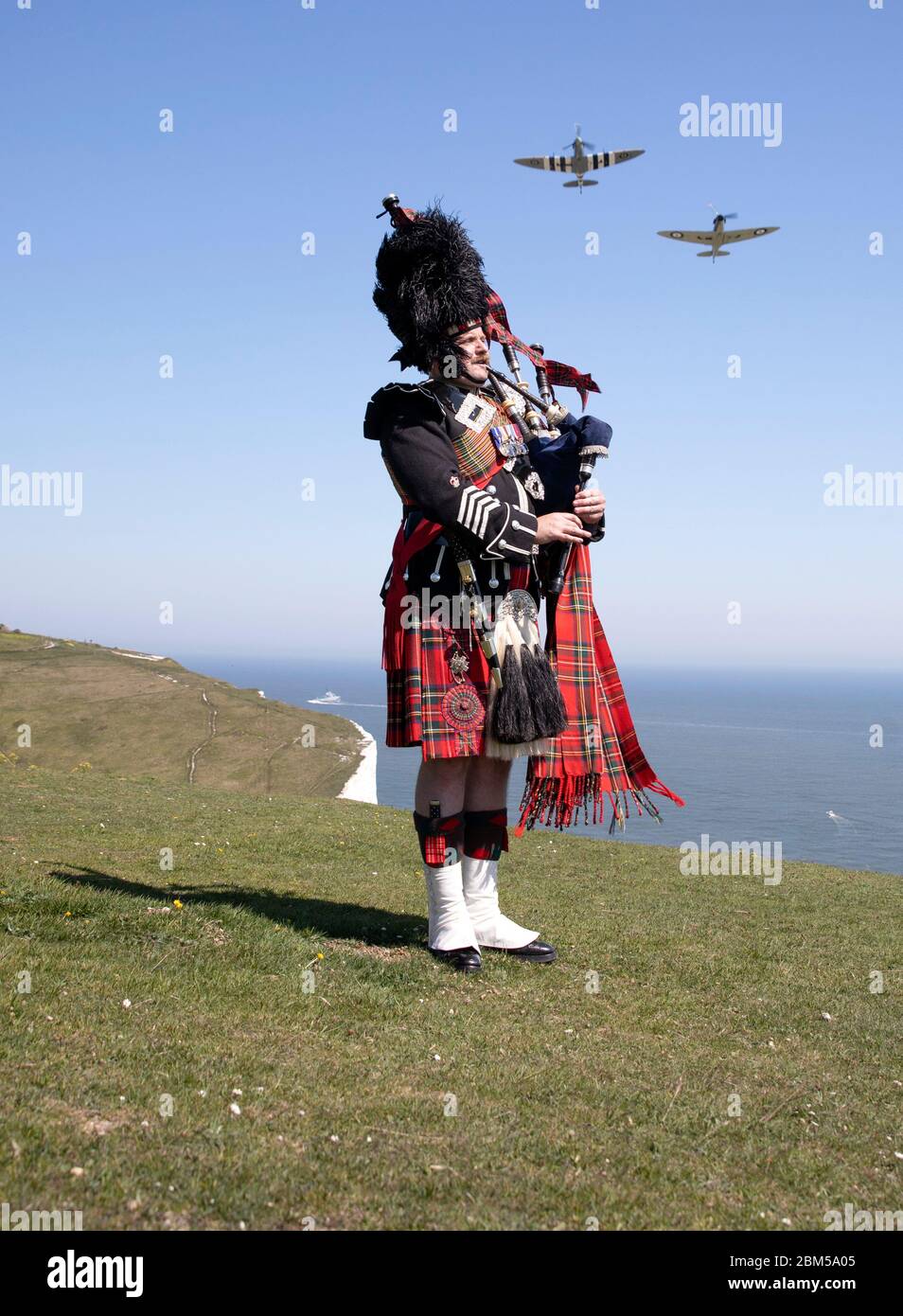 EMBARQUEMENT LE vendredi 0001 MAI 08 le major de corsaire Andy Reid des Scots Guards joue ses pipes sur les falaises de Douvres, Kent, tandis que deux Spitfires du vol commémoratif de la bataille de Grande-Bretagne survoleront, avant les commémorations du 75e anniversaire de la Ve journée. Banque D'Images