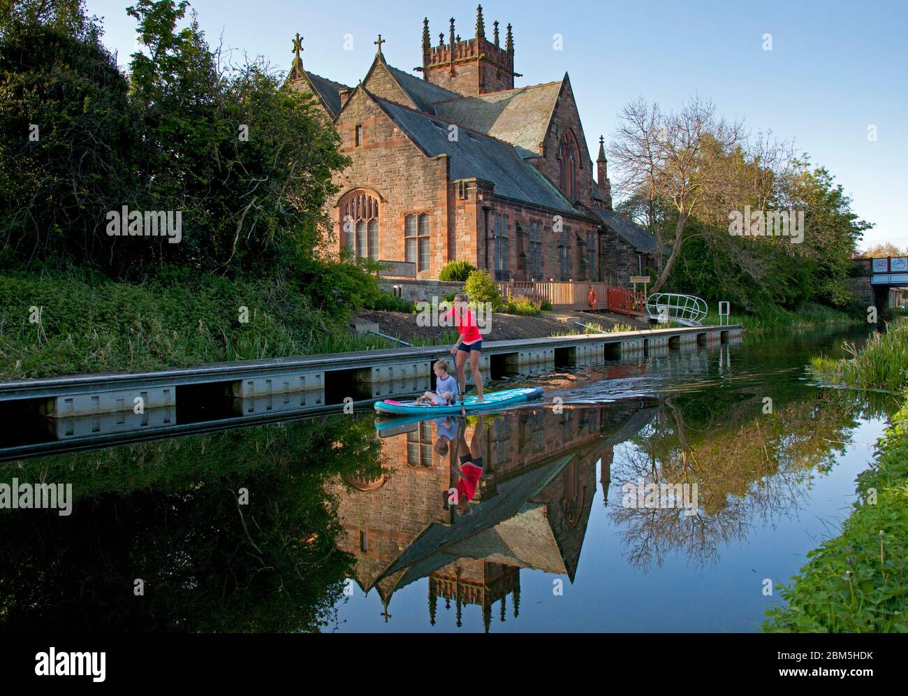 Union canal, Édimbourg, Écosse, Royaume-Uni. 7 mai 2020. Au petit matin, la température du soleil de 9 degrés, le canal Union offre de nombreuses occasions d'admirer des vues panoramiques et de se rapprocher de la nature, photographiée : femme et garçon sur un paddle-board debout avec église en arrière-plan et réflexion dans les eaux fixes. La voie navigable s'étend du centre historique d'Édimbourg jusqu'à Falkirk. Crédit : Arch White/Alamy Live News Banque D'Images