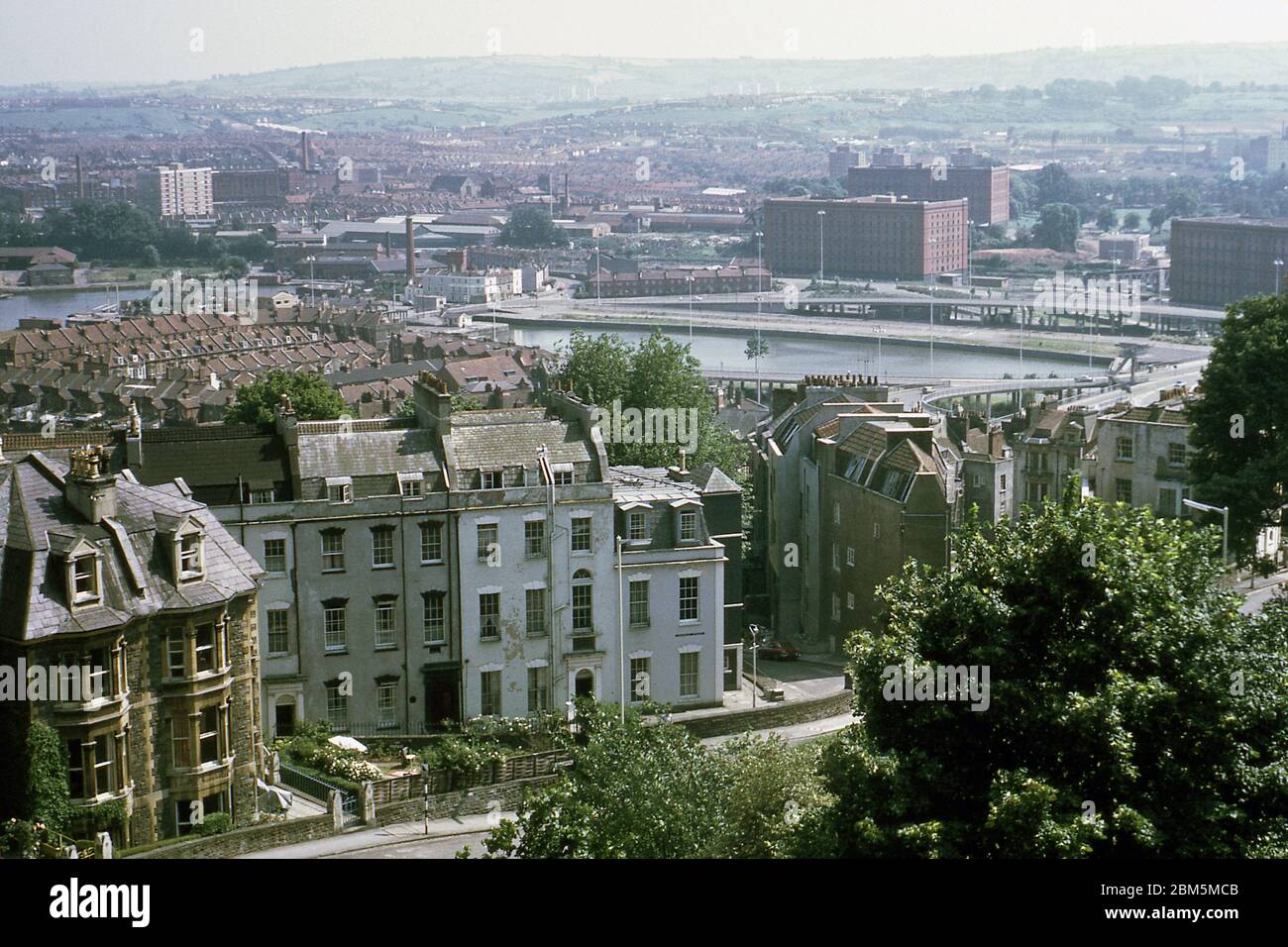 Bristol dans les années 60 et 70 : vue du Royal York Crescent à Clifton vers les quais de la ville, montrant les bâtiments du Cornwallis Crescent divisés en appartements loués par des étudiants de l'université de Bristol dans les années 60 et 70. En arrière-plan, une partie du réseau routier du bassin de Cumberland, qui a ouvert ses portes en 1965, et les entrepôts de stockage construits au début du XXe siècle pour répondre à un boom des importations de tabac, à mesure que les prix des cigarettes chutaient et que les ventes augmentaient suite au développement de machines à cigarettes. Cette photo a été prise en juin 1970. Banque D'Images