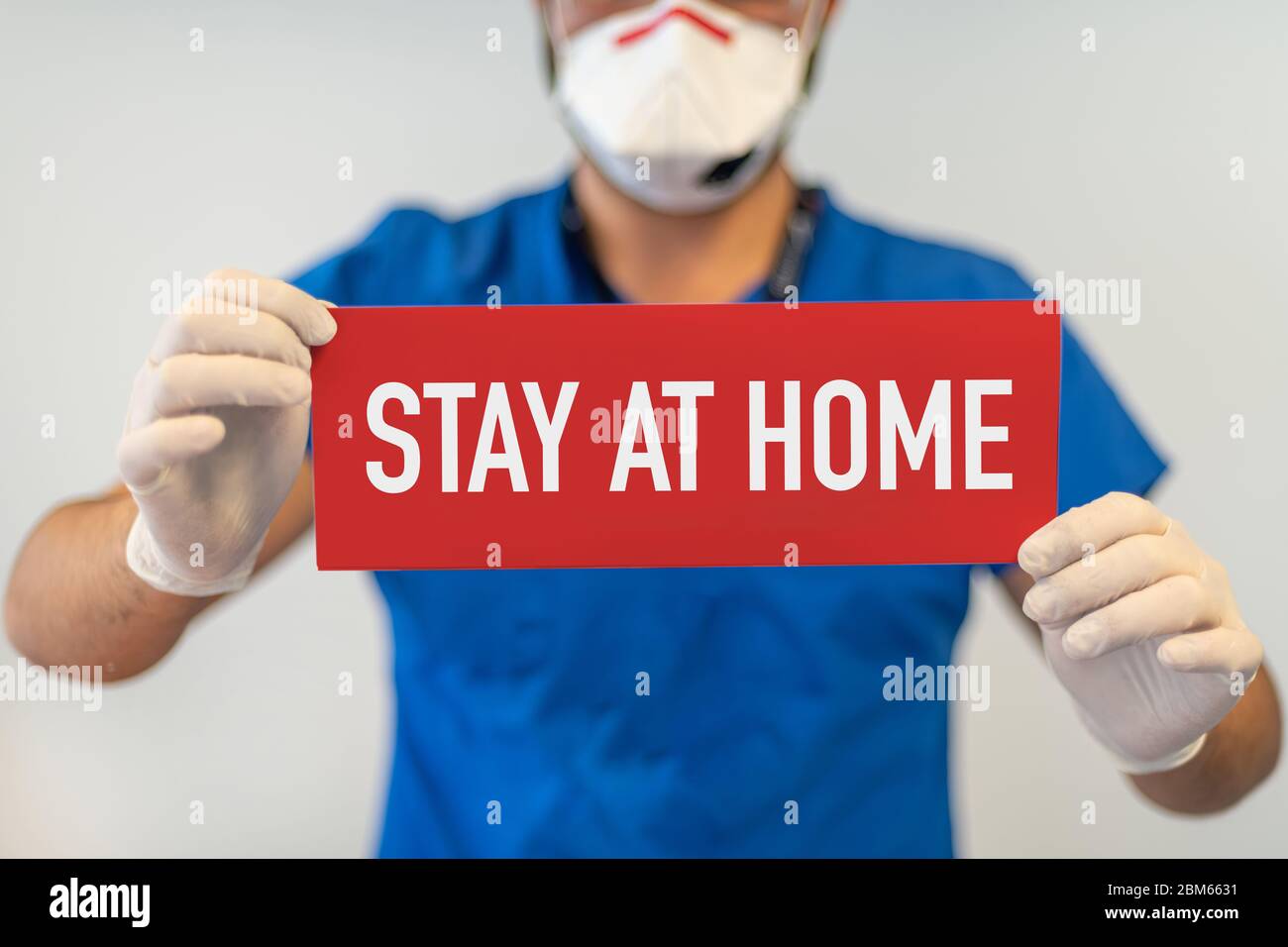 Un médecin avec un papier rouge avec rester à la maison tenu à portée de main, protéger contre le coronavirus ou l'épidémie Covid-19 Banque D'Images