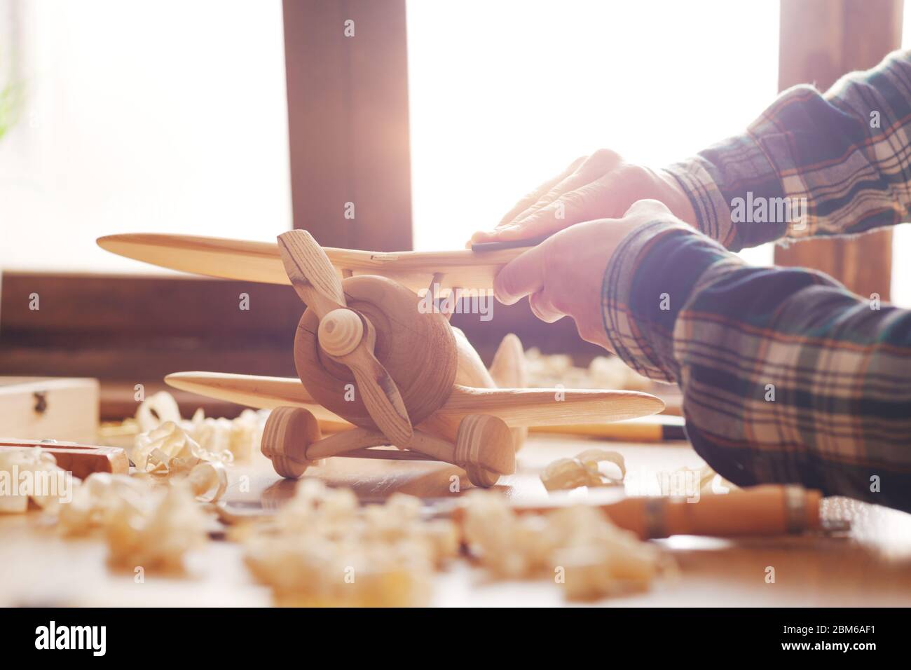 Artisan d'un lissage de surface en bois avec du papier de verre, les outils et les copeaux de bois tout autour, les mains close up Banque D'Images