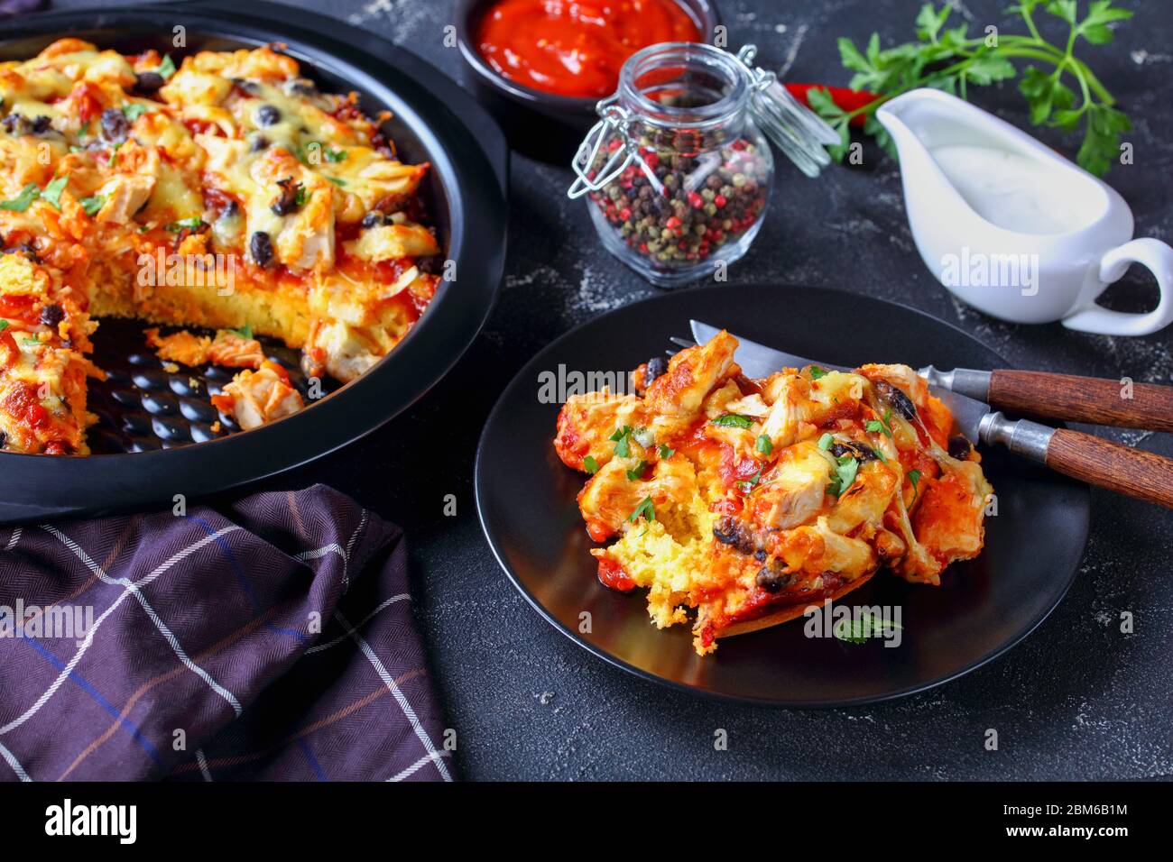 Tarte tamaale ou cocotte de poulet tirée avec croûte de maïs, cheddar, haricots noirs et sauce tomate, servie sur un plat de cuisson noir, servi sur un bois Banque D'Images