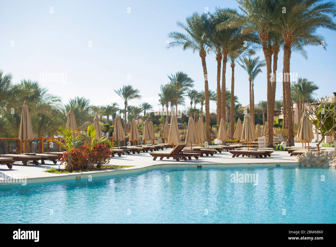 Chaises longues d'été sous un parapluie sur la mer de sable piscine et palmiers dans l'hôtel Egypte, Charm el-Cheikh, concept temps de Voyage sans personnes Banque D'Images