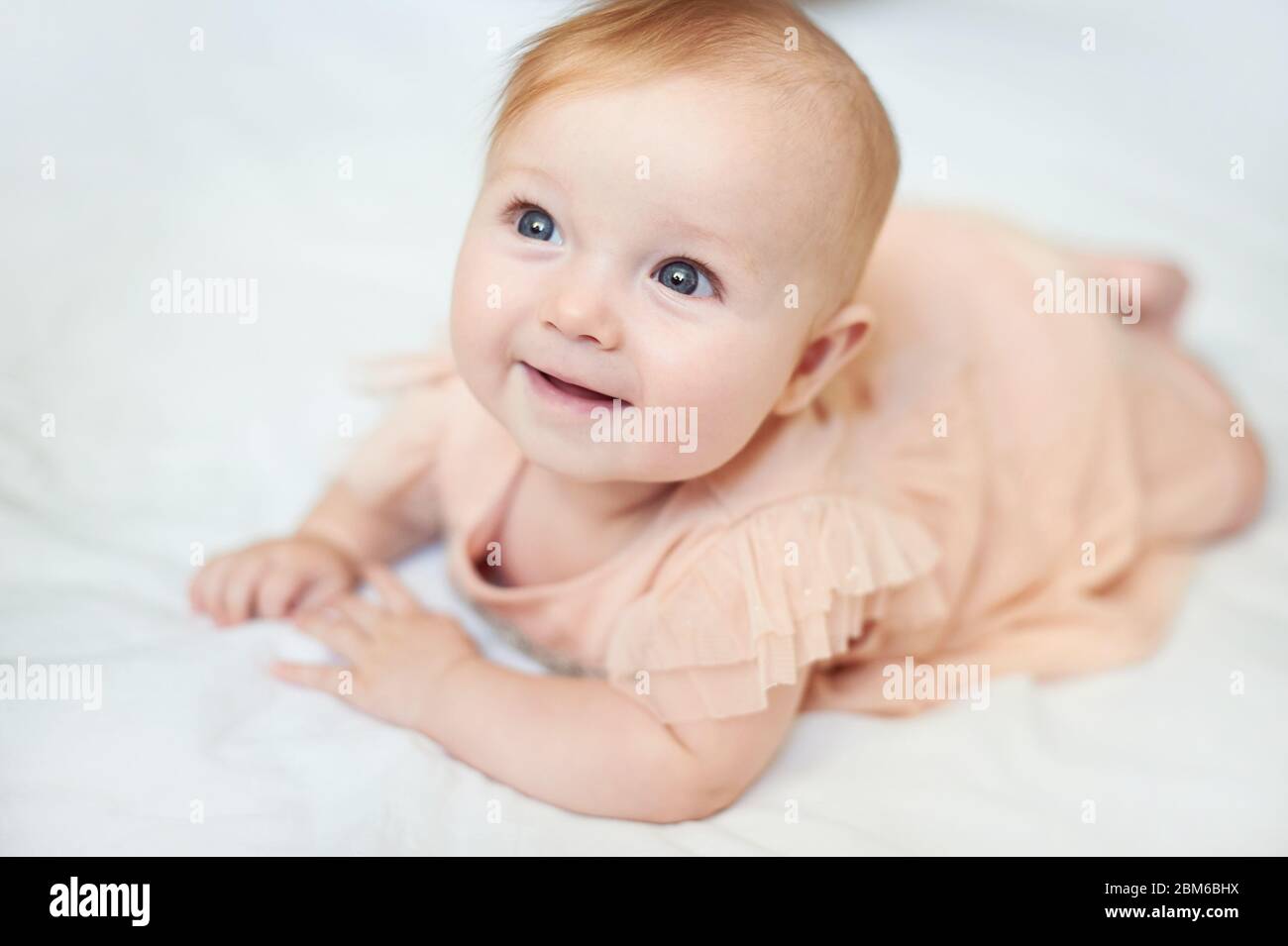 Portrait d'un doux sourire de bébé portant une robe rose en studio Banque D'Images