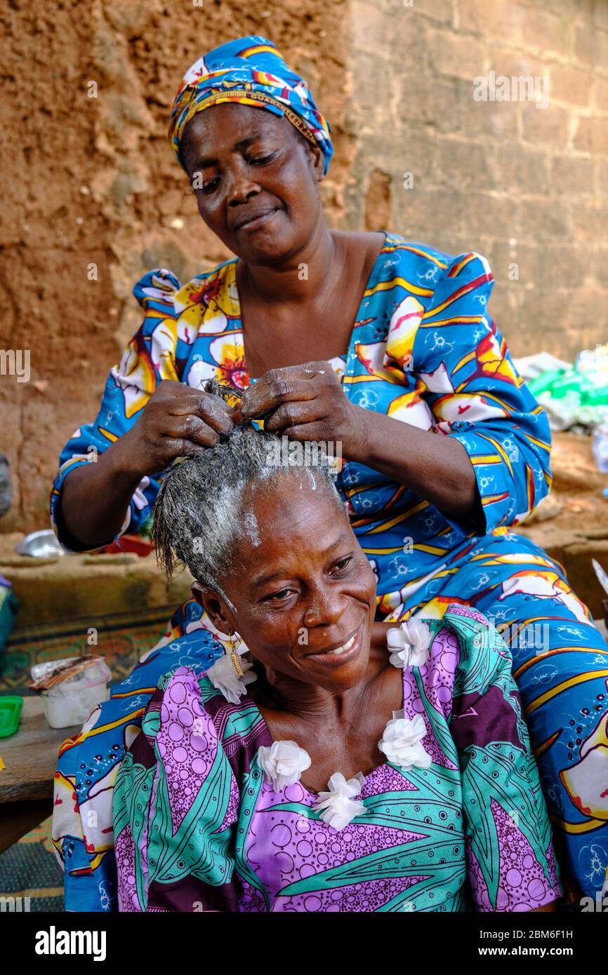 Femme habillée en costume africain coloré prenant soin des cheveux d'une autre femme. Banque D'Images