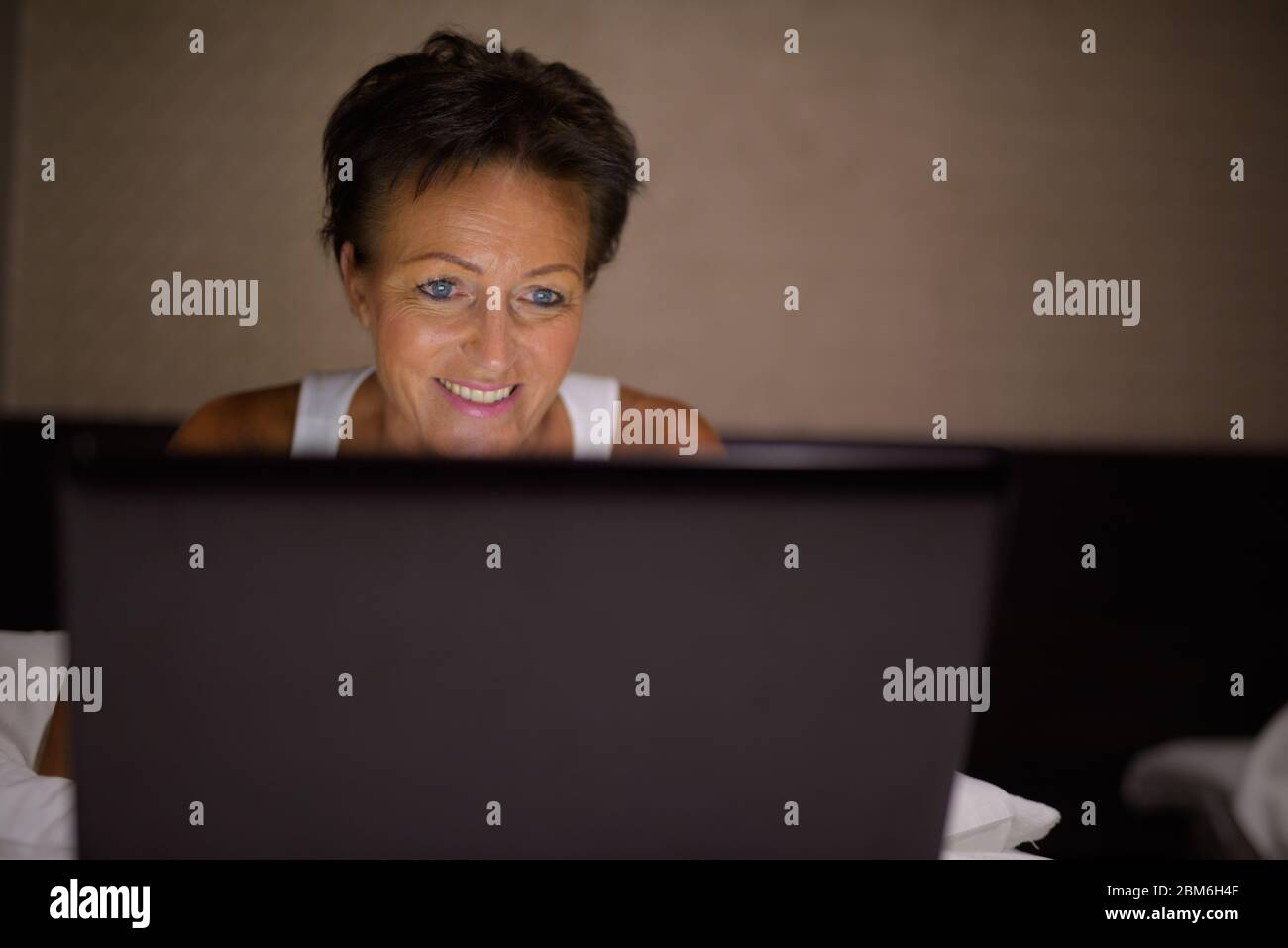 Bonne mature belle femme touristique utilisant un ordinateur portable dans la chambre Banque D'Images