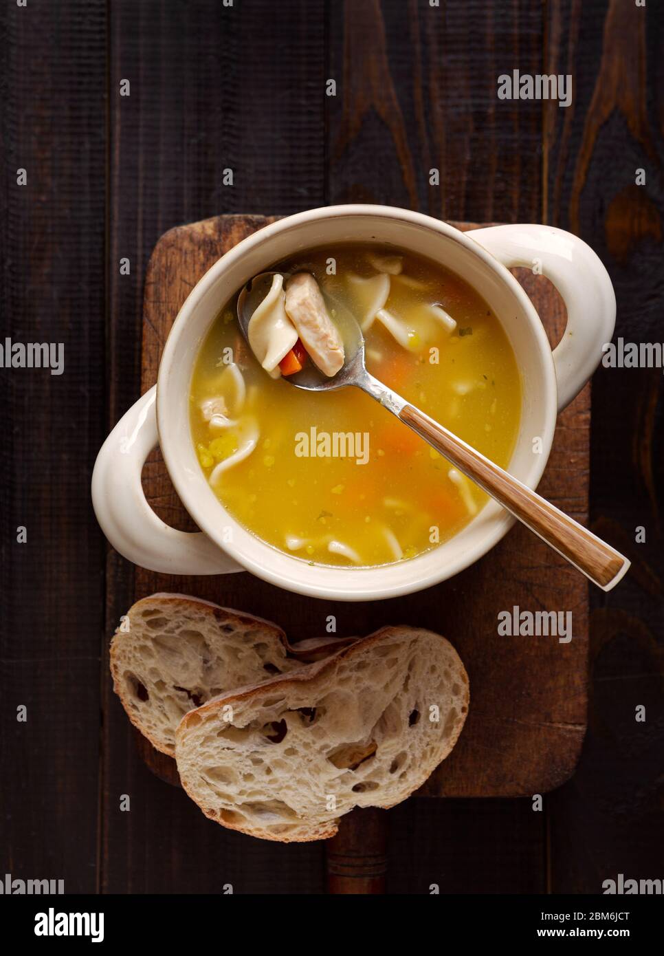 Vue en hauteur de la soupe de nouilles de poulet avec du pain sur une surface en bois Banque D'Images