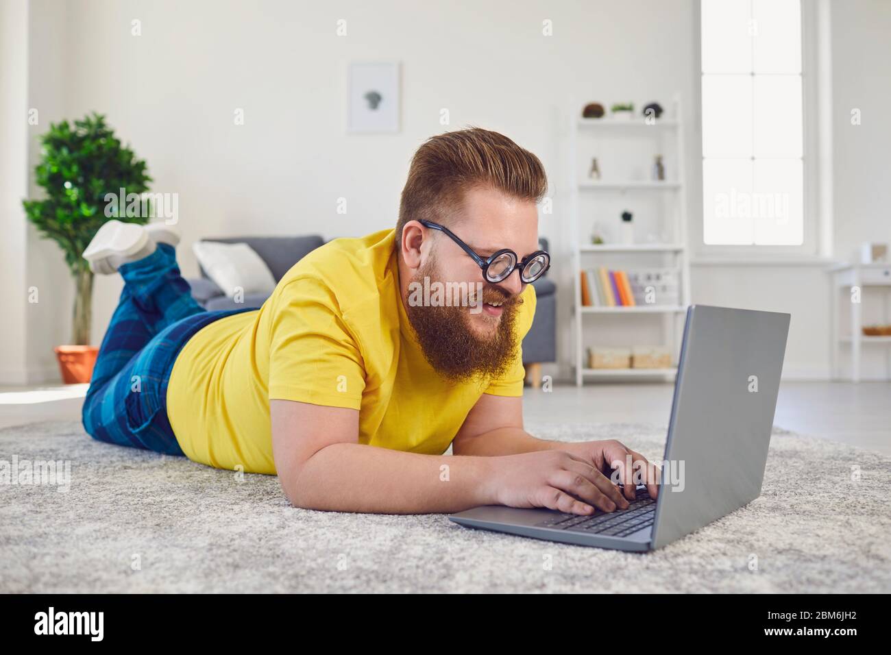 Travailler en ligne au bureau à domicile. Drôle homme travaille en ligne  communique appel chat vidéo en utilisant l'ordinateur portable couché sur  le sol à la maison Photo Stock - Alamy