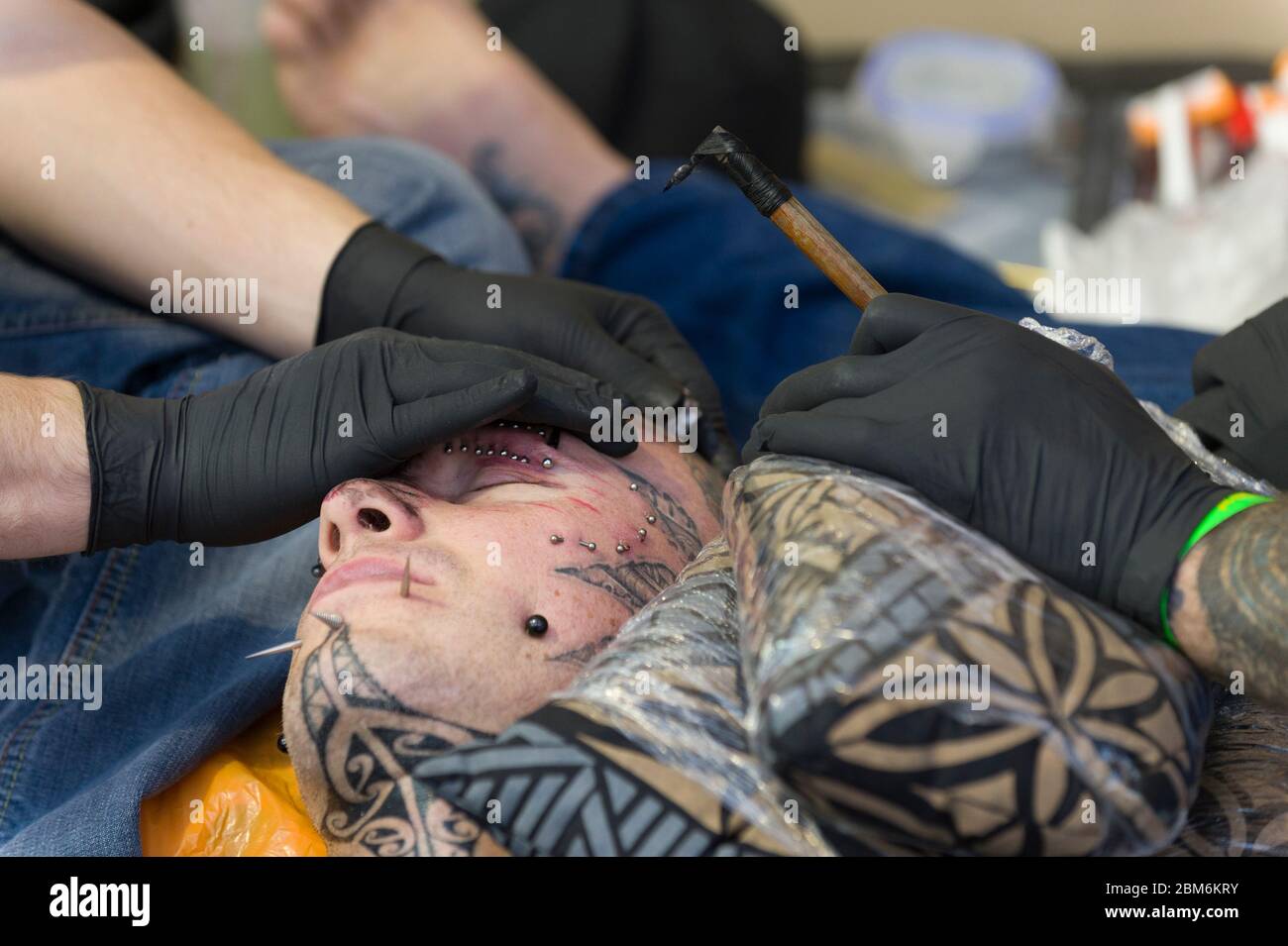 Homme ayant son visage tatoué par la méthode polynésienne. Cette méthode implique un peigne d'aiguilles qui est taraudé à la peau avec le bâton à la main. Le long Banque D'Images