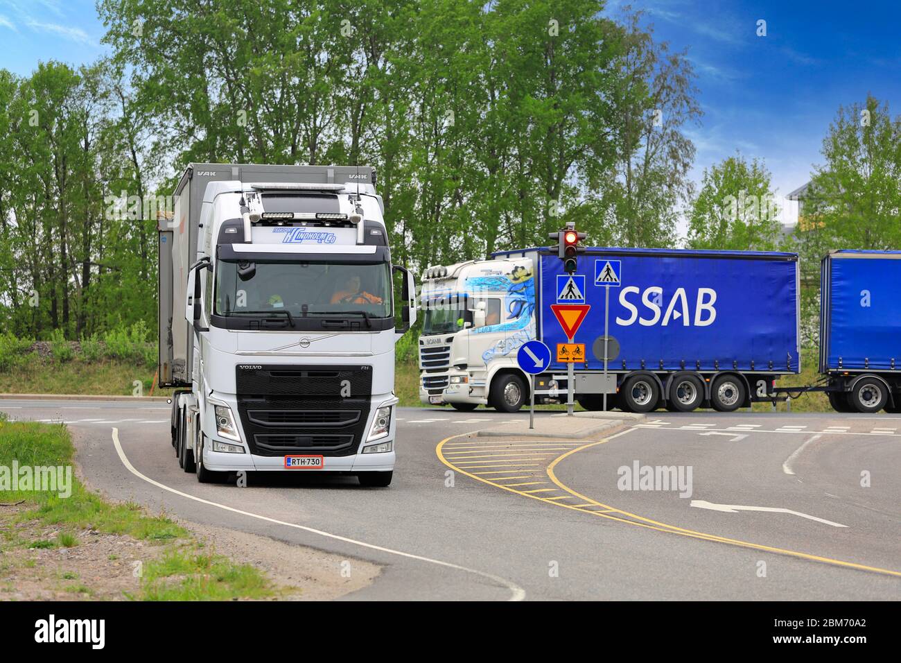 Deux camions Volvo et Scania blancs personnalisés de transport K. Lindholm & Co transportant des marchandises sur l'intersection de l'autoroute. Raasepori, Finlande. 24 mai 2019. Banque D'Images