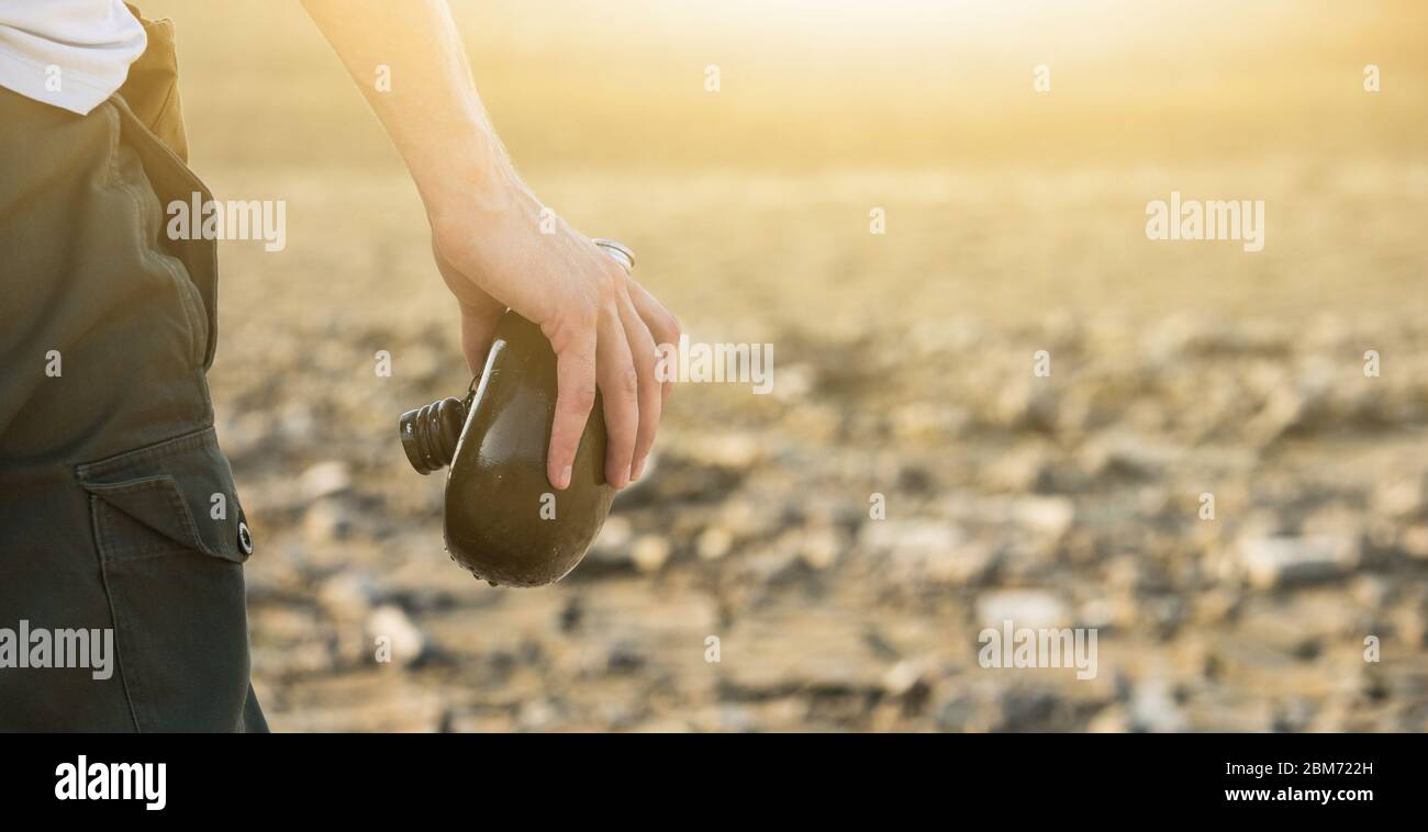 Homme avec une fiole dans le désert. Sécheresse et pénurie d'eau causées par le réchauffement climatique Banque D'Images