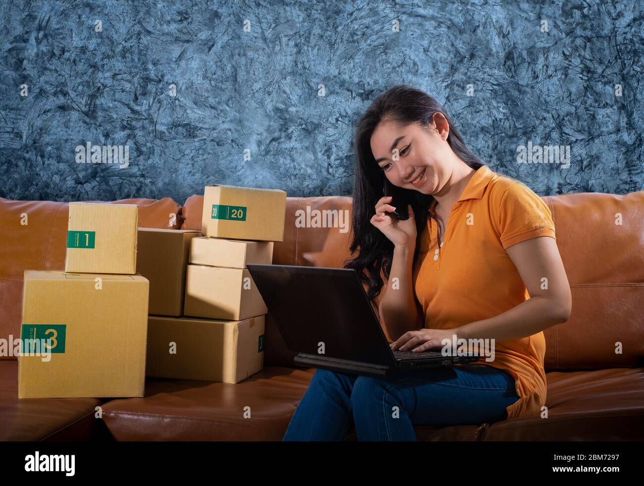 Portrait ennuyé Asie jeune femme est assise sur le canapé à sa chambre, les femmes ont utilisé le téléphone mobile sur fond de mur de béton, UNE dame s'ennuie parce que la vente Banque D'Images