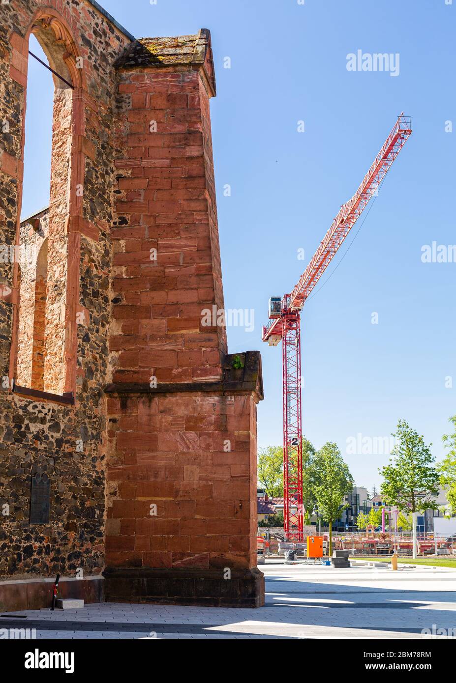 Grue de construction à côté de la vieille église. Construction d'un nouveau domaine de logement. Développement de la ville. Architecture ancienne et moderne. Murs en pierre. Banque D'Images