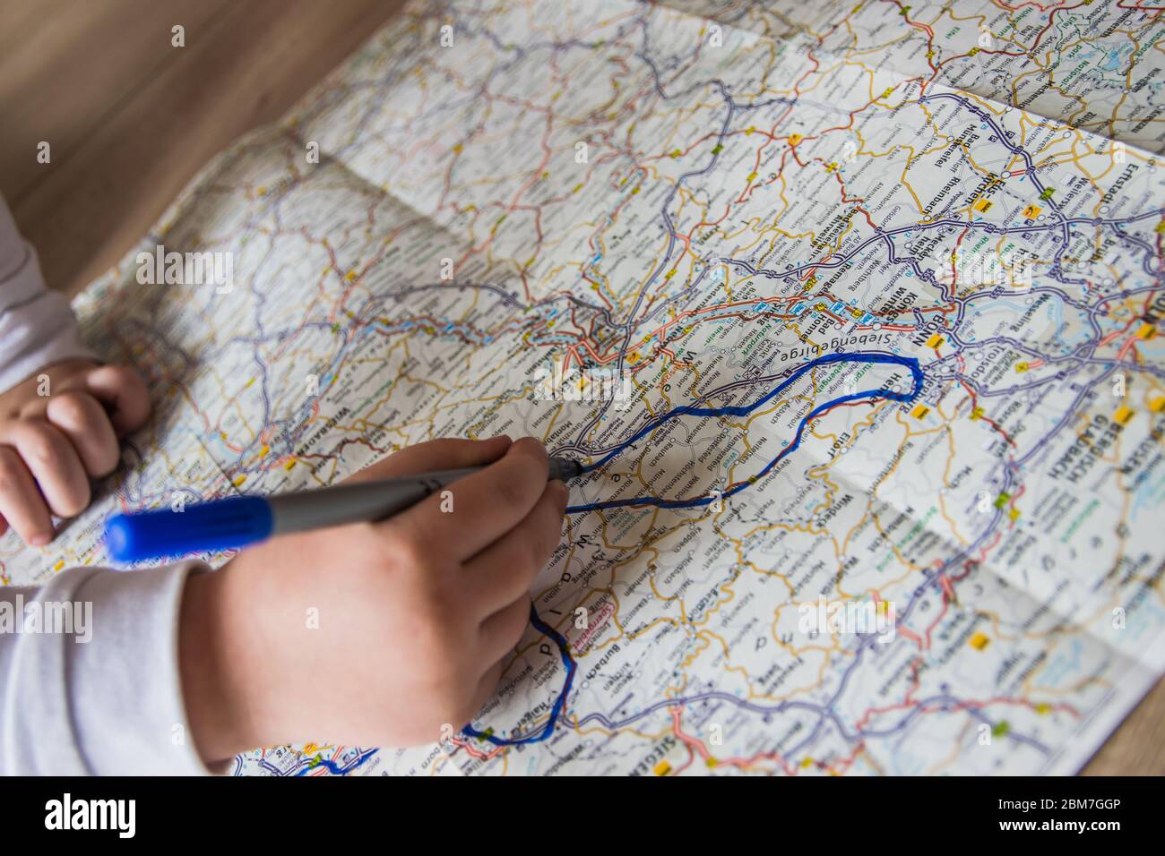 Main de l'enfant écrivant sur une carte avec un stylo bleu. Les enfants tiennent la main avec un stylo feutre. Voyage et vacances avec les enfants. Concept de repos d'été. Banque D'Images