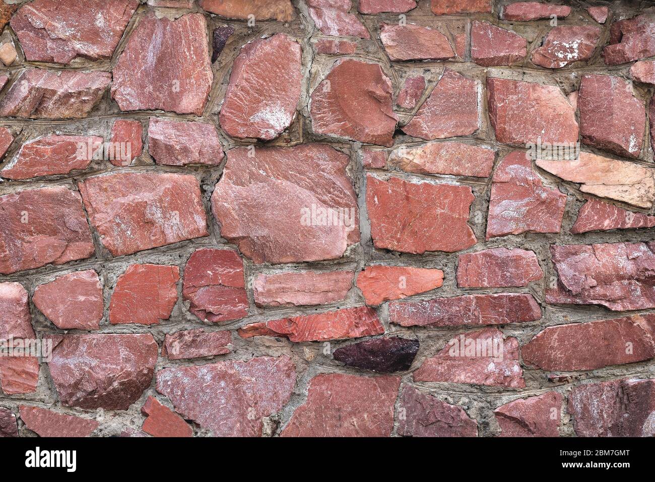 Le mur de grandes pierres de granit brut de couleur rouge, arrière-plan granit non uniforme crouse up Banque D'Images