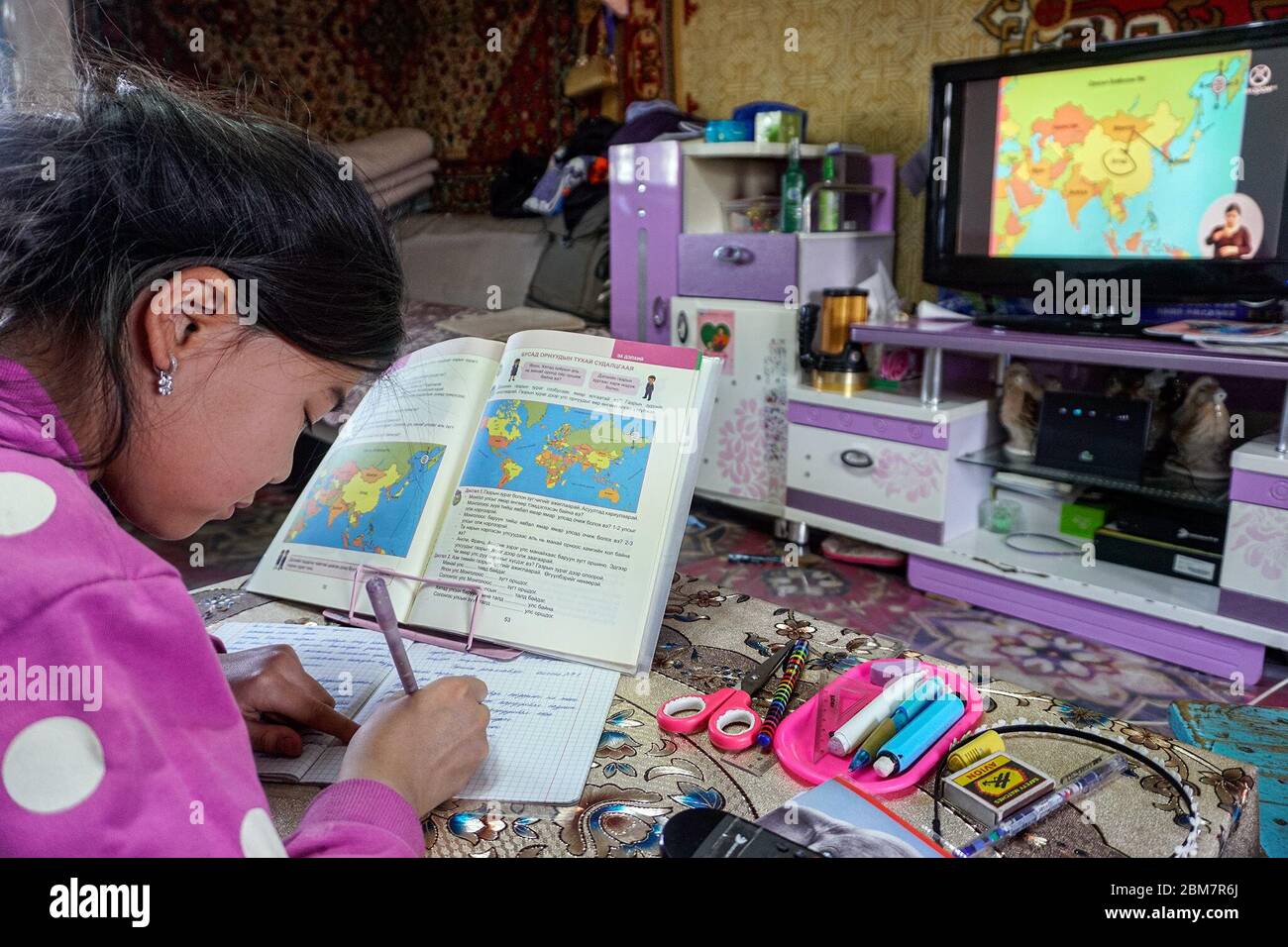 Khulan Tserennadmid, 9 ans, prend des notes en observant une leçon télévisée pour les élèves de troisième année intitulée « humains et environnement » chez elle à Murun, au centre de la province mongole de Khuvsgul. Les activités de la maternelle et de l'école à tous les niveaux sont suspendues, de sorte que le gouvernement a passé à l'enseignement des cours en ligne et à la télévision. (Dolgormaa Sandagdorj, GPJ Mongolie) Banque D'Images