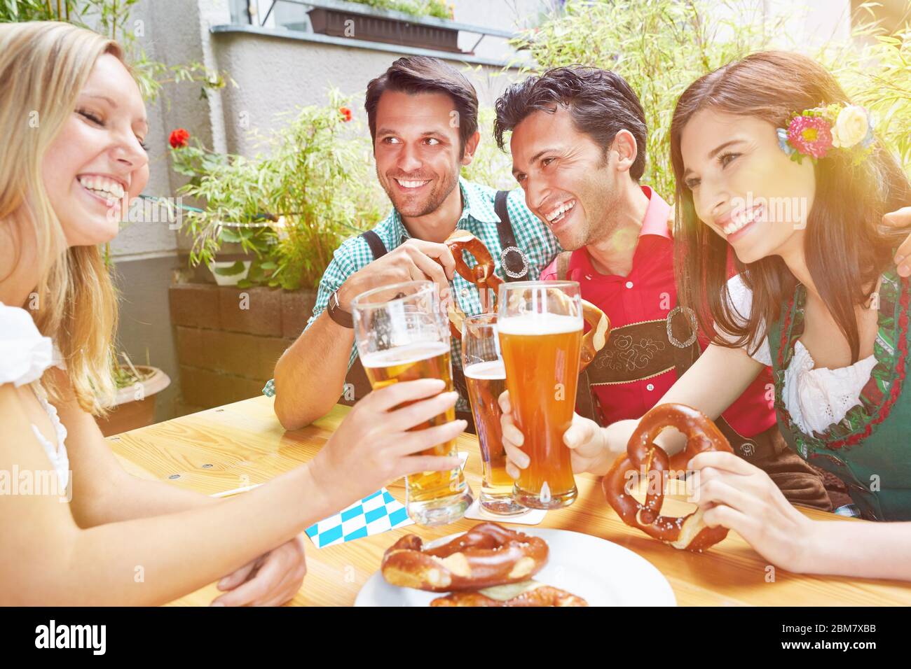 Rire des amis dans le jardin de bière en Bavière clink des verres de bière Banque D'Images
