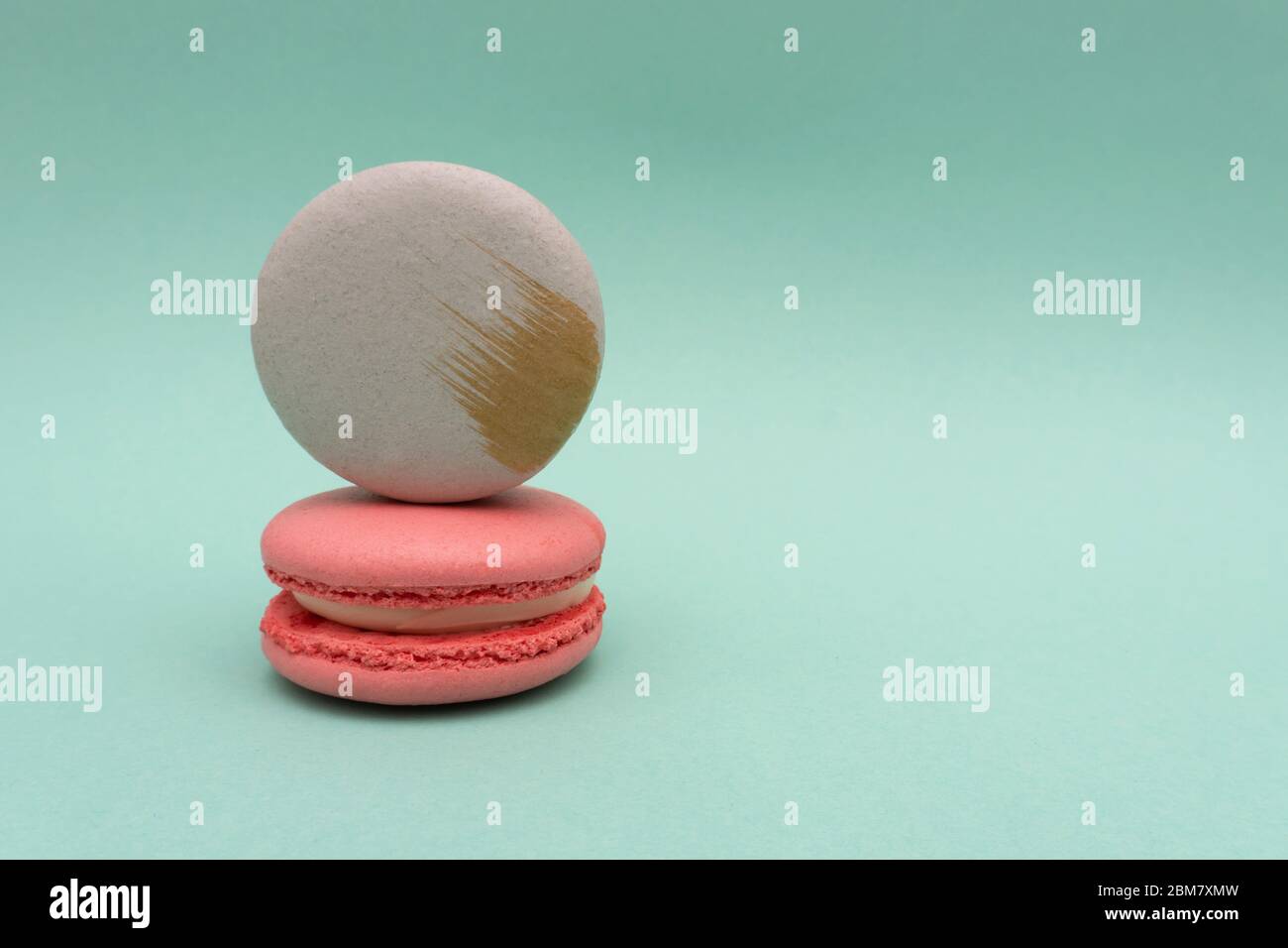 Macaron gris sur macaron rose fraise sur fond menthe ou turquoise Banque D'Images