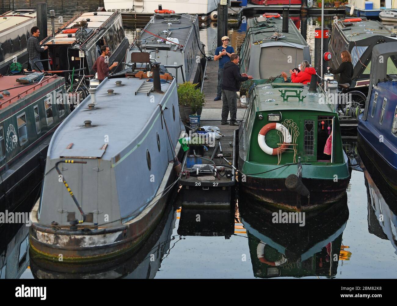 Les gens applaudissent à côté de leurs bateaux au bassin de Limehouse à Londres lorsqu'ils se joignent aux applaudissements de jeudi au cours du Clap national pour que les soignants reconnaissent et soutiennent les travailleurs du NHS et les soignants qui luttent contre la pandémie du coronavirus. Banque D'Images