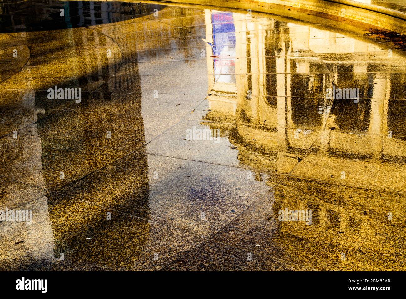 Reflet partiel de l'Alte Oper, Francfort-sur-le-main, Allemagne, dans la zone pavée humide autour de la fontaine Lucae (Lucae-Brunnen). Banque D'Images