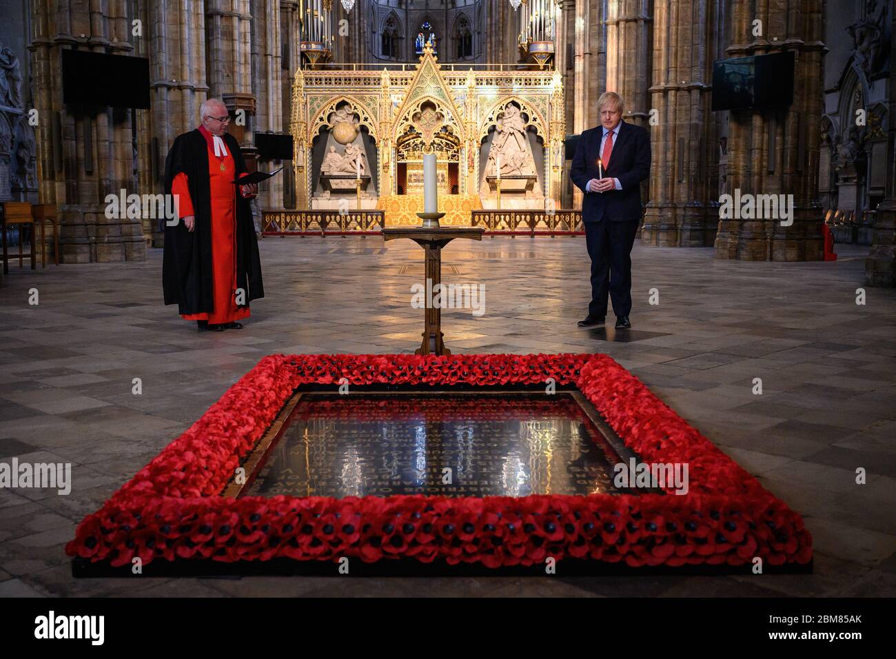 Le doyen de Westminster, le très révérend David Hoyle (à gauche) lit une prière alors que le Premier ministre Boris Johnson allume une bougie à la tombe du guerrier inconnu à l'abbaye de Westminster à Londres, avant les commémorations pour marquer le 75e anniversaire de la Ve journée. Banque D'Images