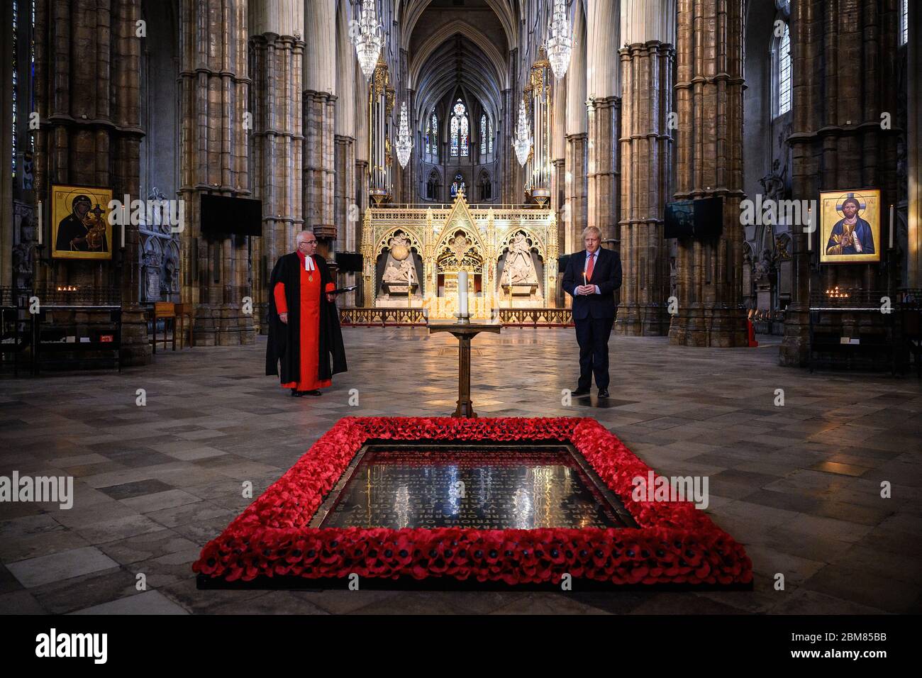 Le doyen de Westminster, le très révérend David Hoyle (à gauche) lit une prière alors que le Premier ministre Boris Johnson allume une bougie à la tombe du guerrier inconnu à l'abbaye de Westminster à Londres, avant les commémorations pour marquer le 75e anniversaire de la Ve journée. Banque D'Images