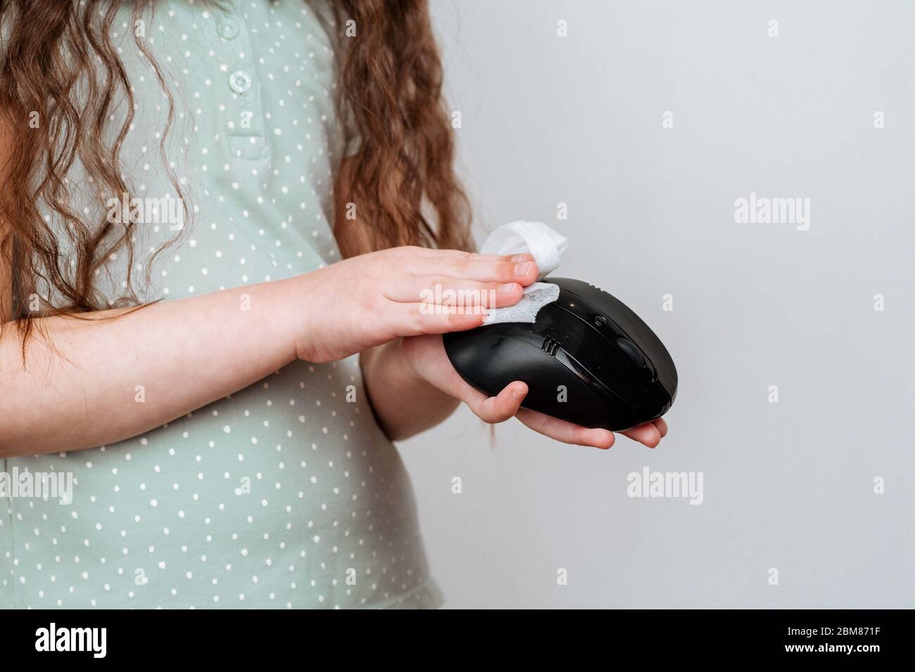 Un enfant désinfecte une souris informatique pour la protéger des virus et des germes. Prévention du coronavirus Banque D'Images