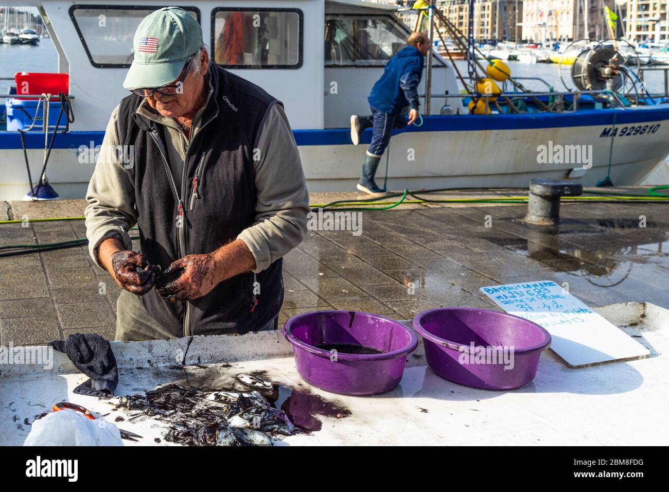 Un vieux pêcheur vendant de la seiche à l'encre noire au marché de poissons de Marseille. Marseille, France, janvier 2020 Banque D'Images