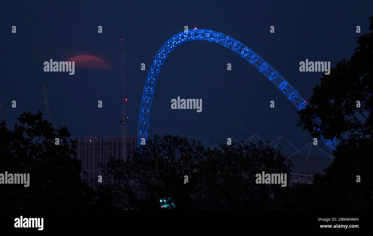 Wembley, Royaume-Uni. 7 mai 2020. La lune de fleurs (signifiant les fleurs de May en fleur), s'élève derrière l'arche du stade Wembley (éclairé en bleu pour les travailleurs du NHS) dans le nord-ouest de Londres. C'est la dernière superlune de 2020, où la lune est la plus proche de la terre (le périgée) et semble 6% plus grande qu'une pleine lune normale. Le stade Wembley est considéré comme un lieu neutre pour accueillir les matchs de la Premier League dans le cadre du projet Restart afin que la saison de football se termine après avoir été suspendue en raison de la pandémie du coronavirus. Credit: Stephen Chung / Alay Live News Banque D'Images